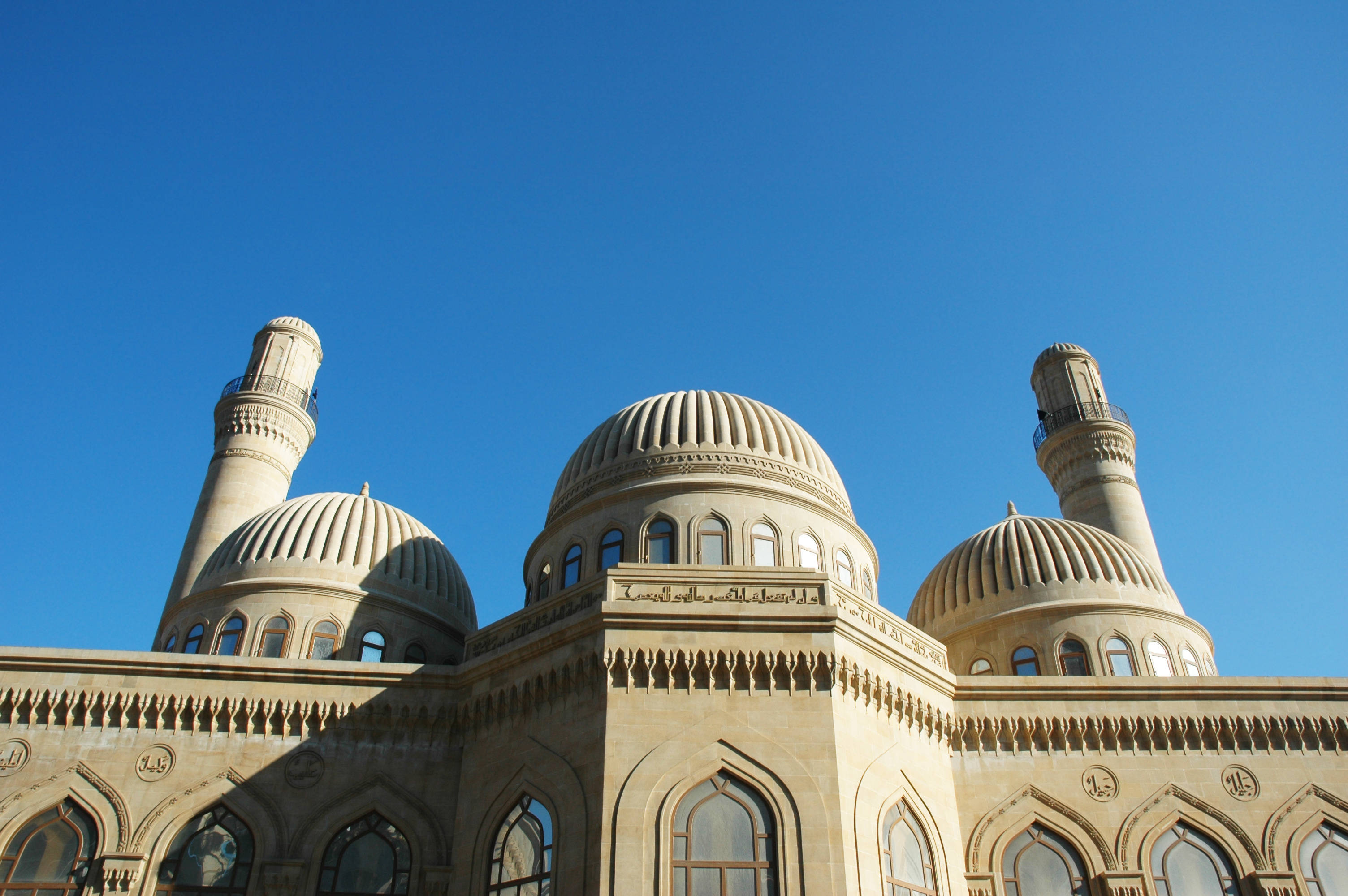 Azerbaijan 桌布 壁紙 — 一座巨大的米色清真寺，擁有三個圓頂和宣禮塔，在明亮的陽光下，矗立在清澈的藍天之下。