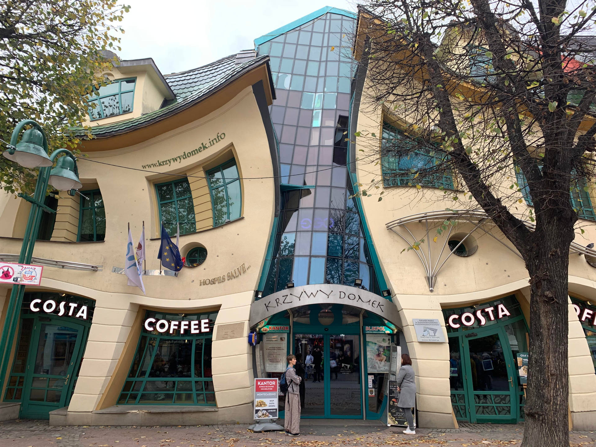 彎曲的現代建築，設有 Costa Coffee 店和秋樹。 — 波蘭 GIF 壁紙