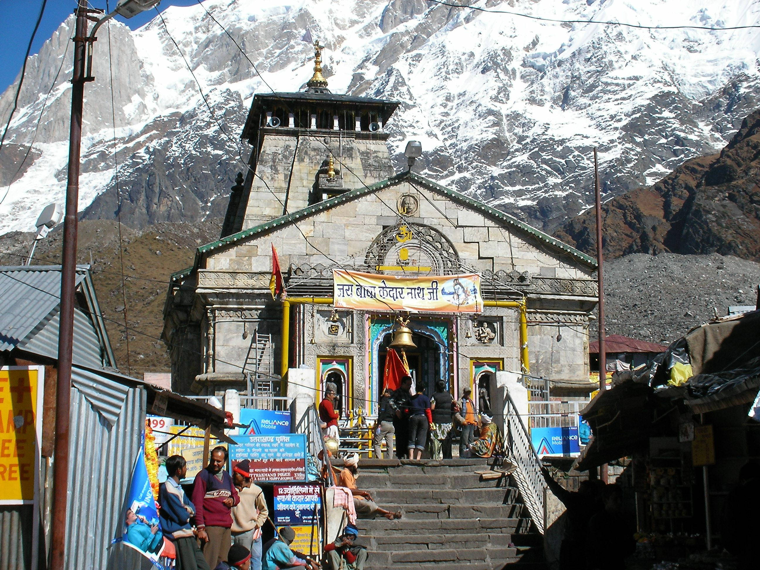Kedarnath 桌布 壁紙 — 一座帶有色彩點綴的石廟矗立在湛藍天空下高聳積雪山腳。