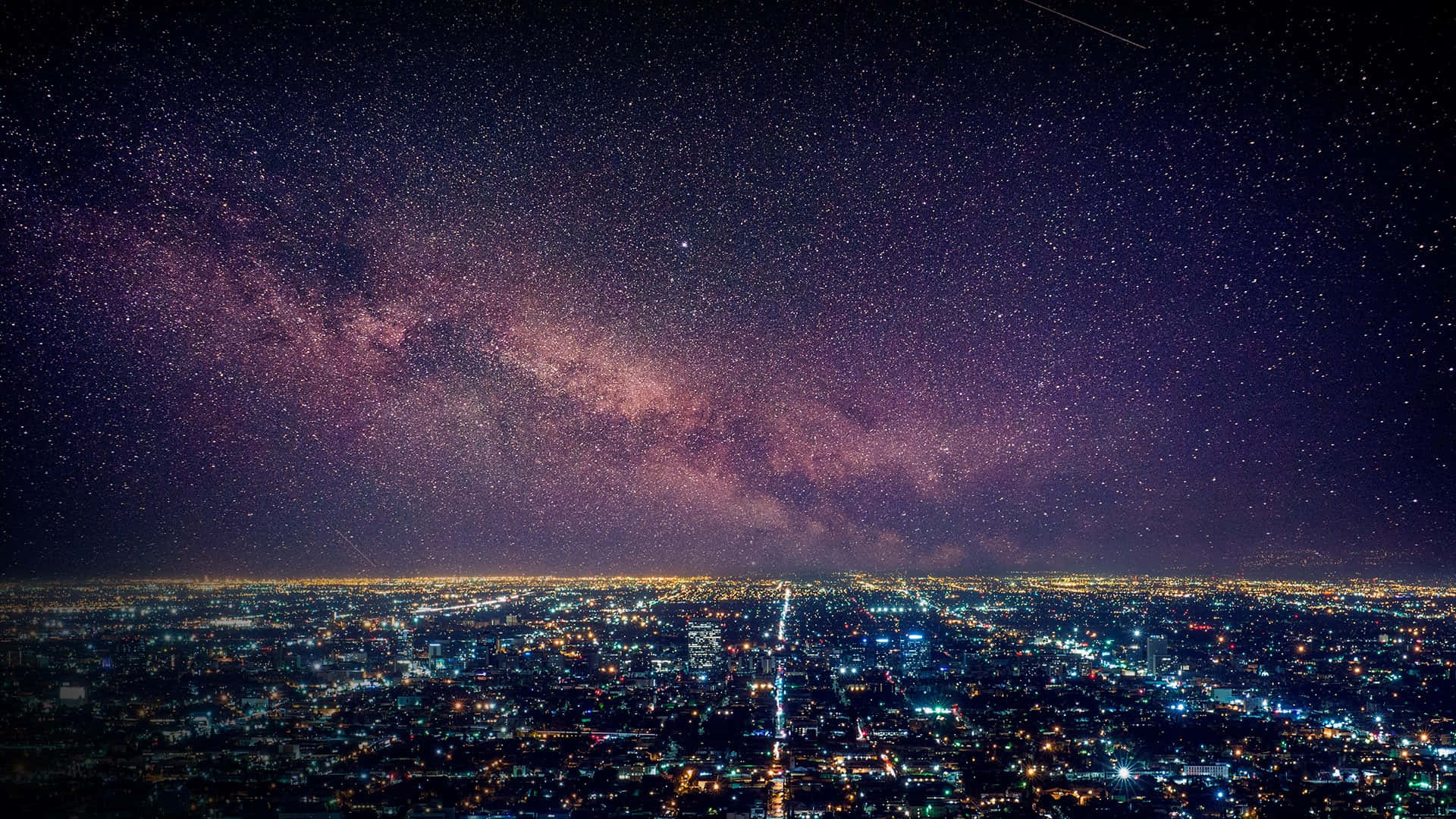 La 桌布 壁紙 — 一座廣闊的城市在令人驚嘆的紫色銀河拱跨夜空下亮起。