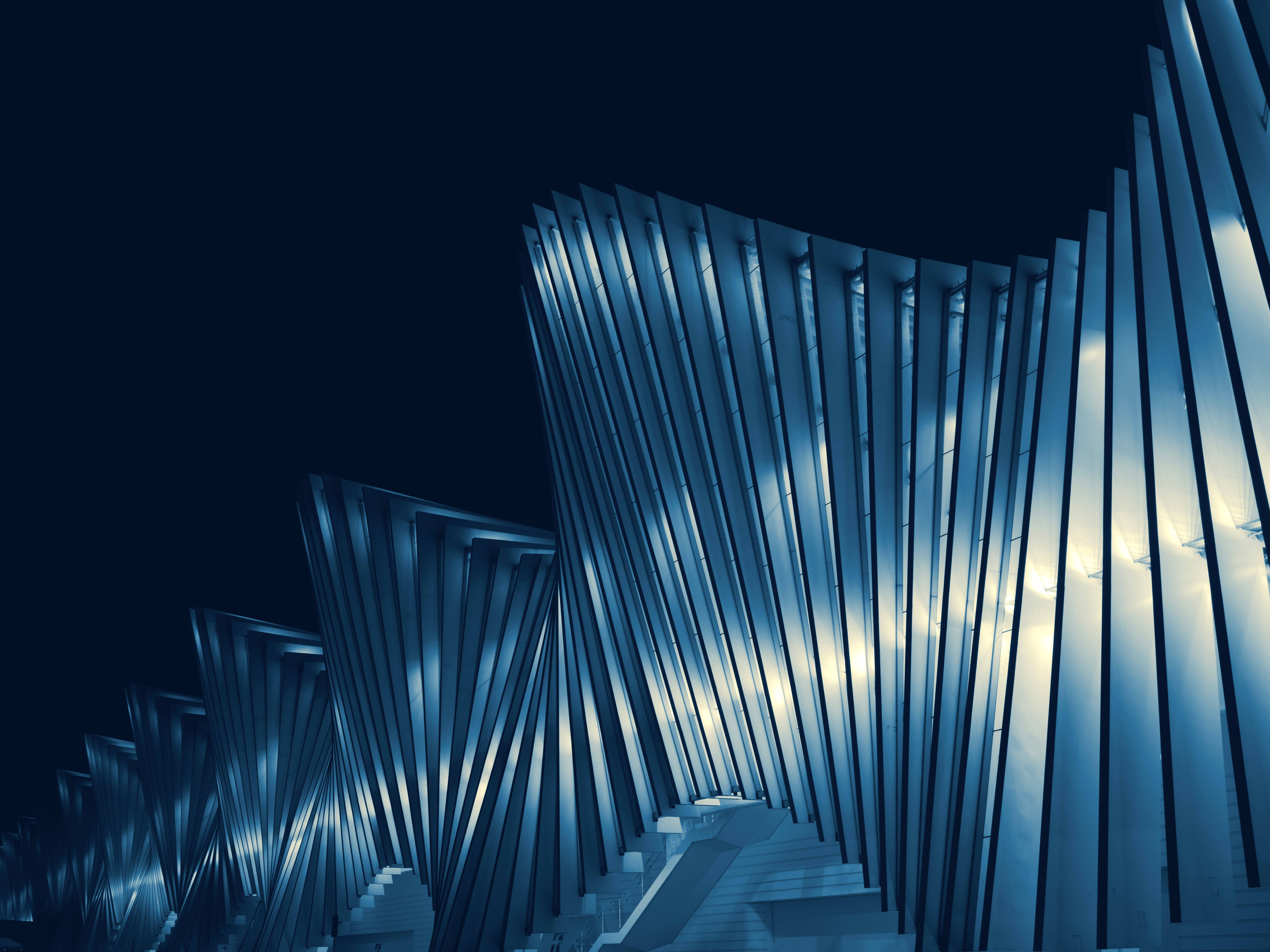 Architecture 桌布 壁紙 — 一座引人注目的現代建築結構，在黑暗的夜空下配有發光的藍色金屬翅片和白色樓梯。