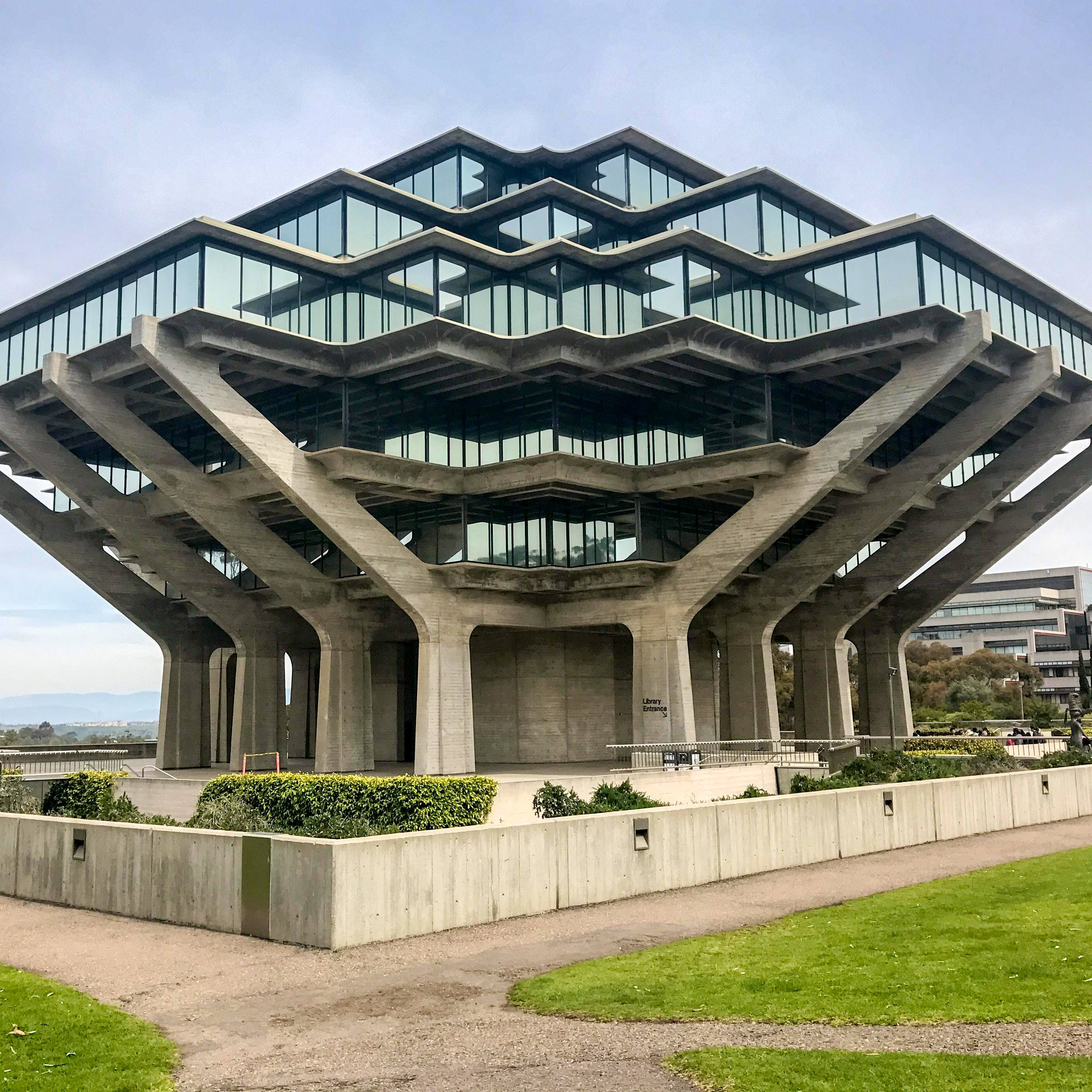 建築 桌布 壁紙 — 一座引人注目的粗獷主義圖書館，擁有分層混凝土支撐和玻璃幕牆，矗立在蒼白的天空下。