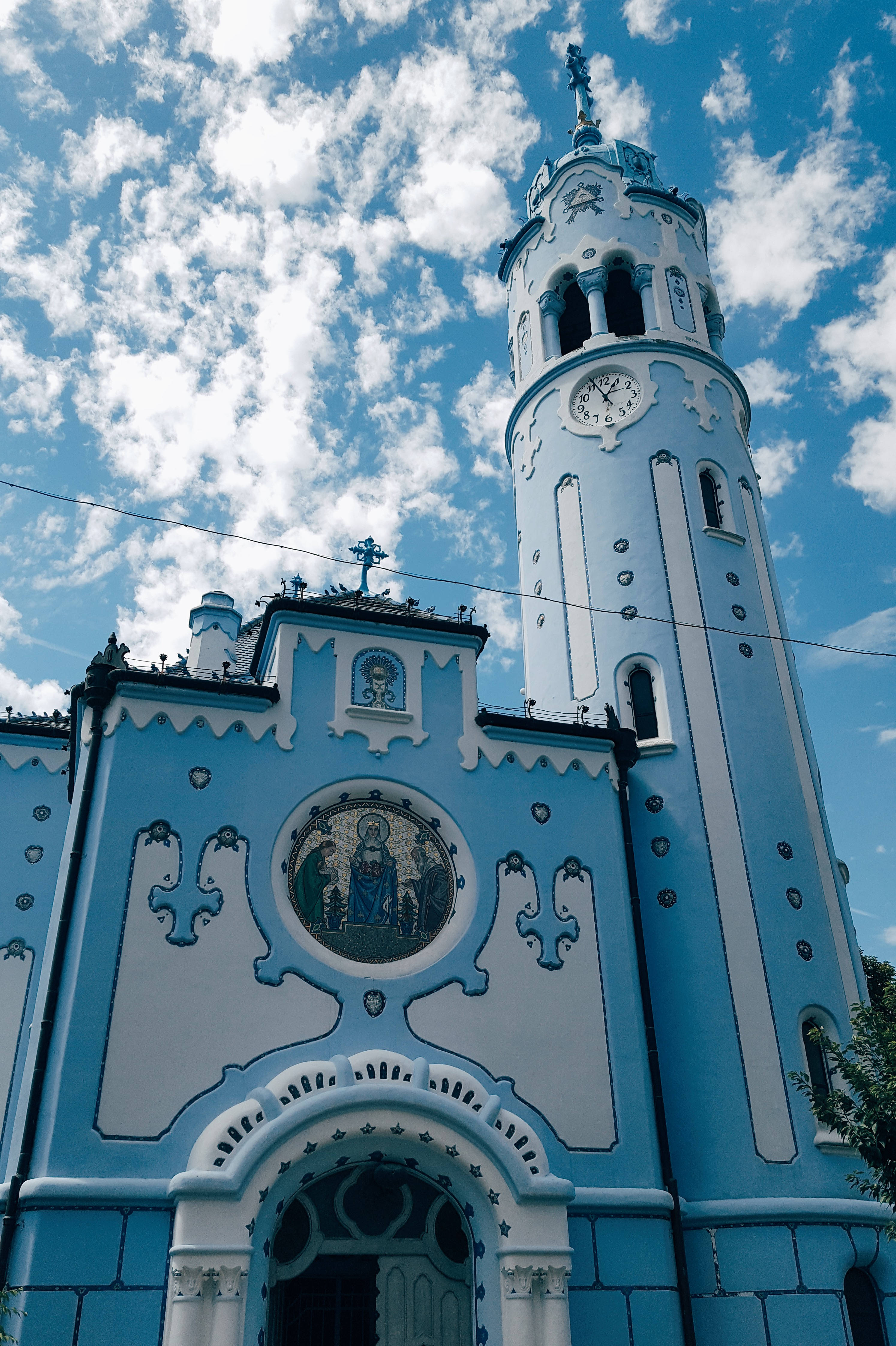 Slovakia 桌布 壁紙 — 一座引人注目的藍白相間華麗教堂，帶有高高的鐘樓，矗立在晴朗的藍天和蓬鬆的白雲下。