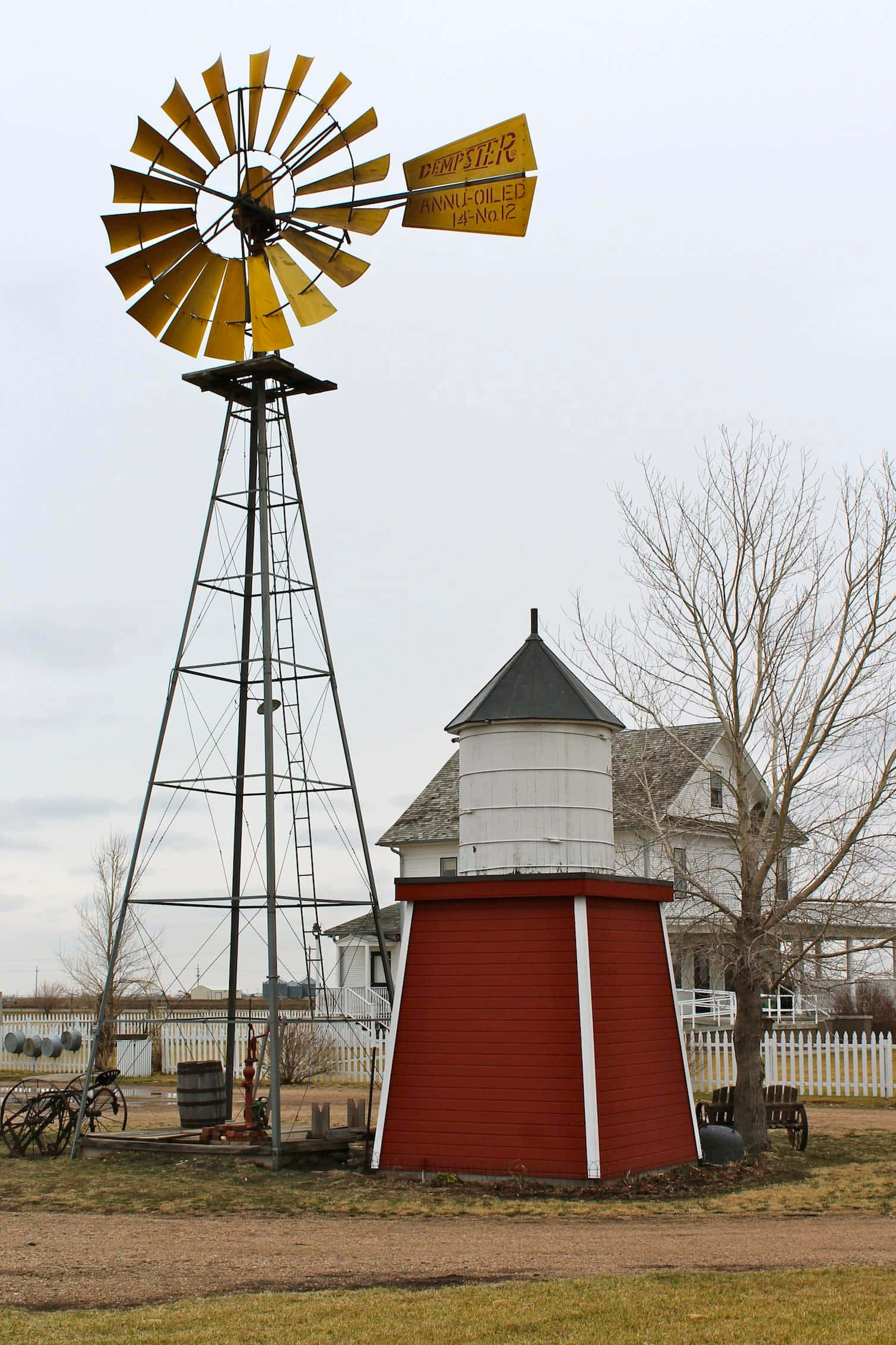 windmill 桌布 壁紙 — 一座復古黃色風車聳立在紅白相間的穀物筒倉旁，位於多雲的鄉村農場。