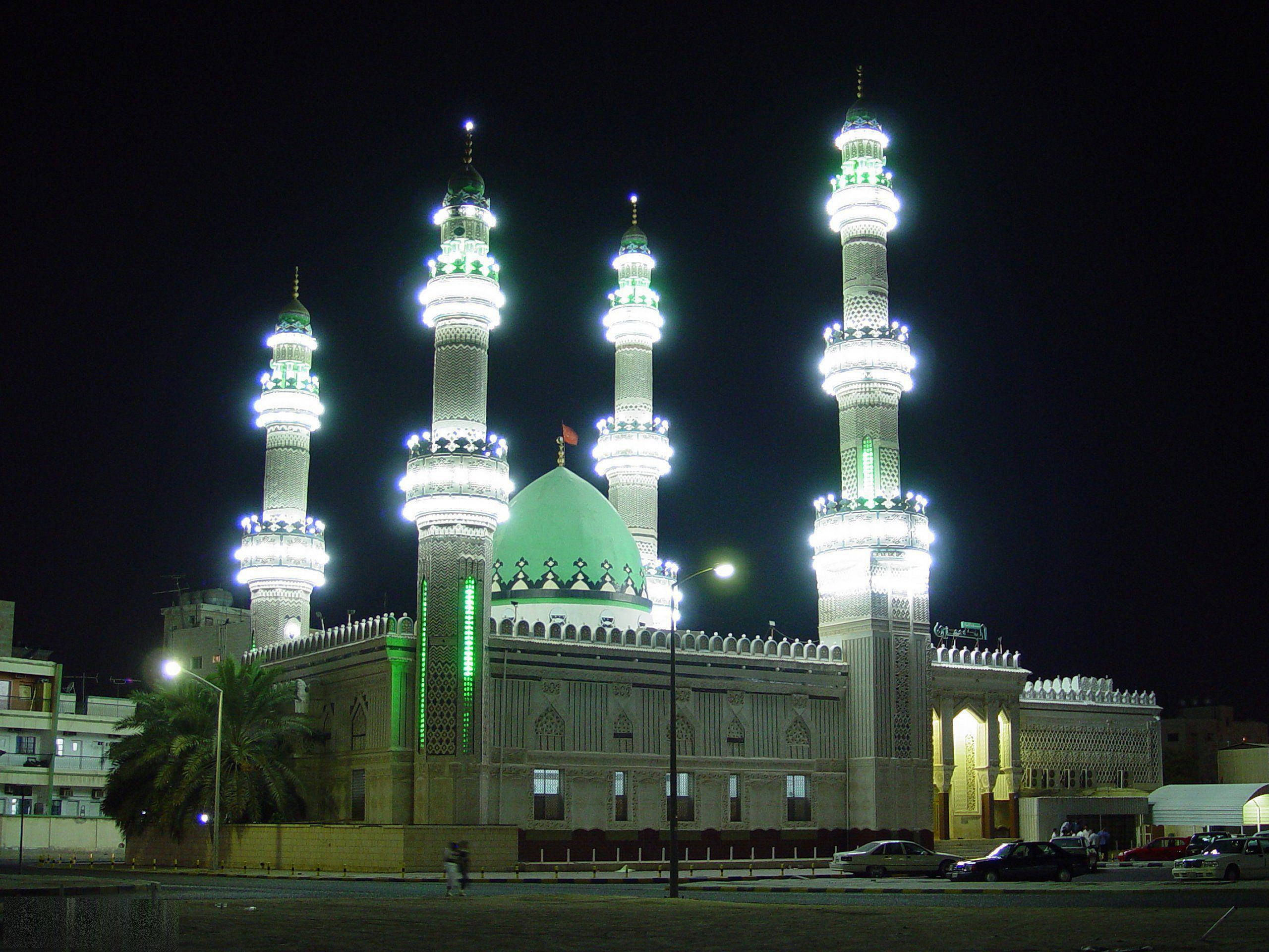 Kuwait 桌布 壁紙 — 一座擁有四個燈光照明宣禮塔和綠色圓頂的大清真寺，在漆黑的夜空下巍然聳立。