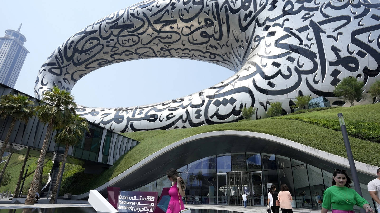Museum 桌布 壁紙 — 一座未來主義建築，在晴朗藍天下，草地上有流動的阿拉伯書法曲線。