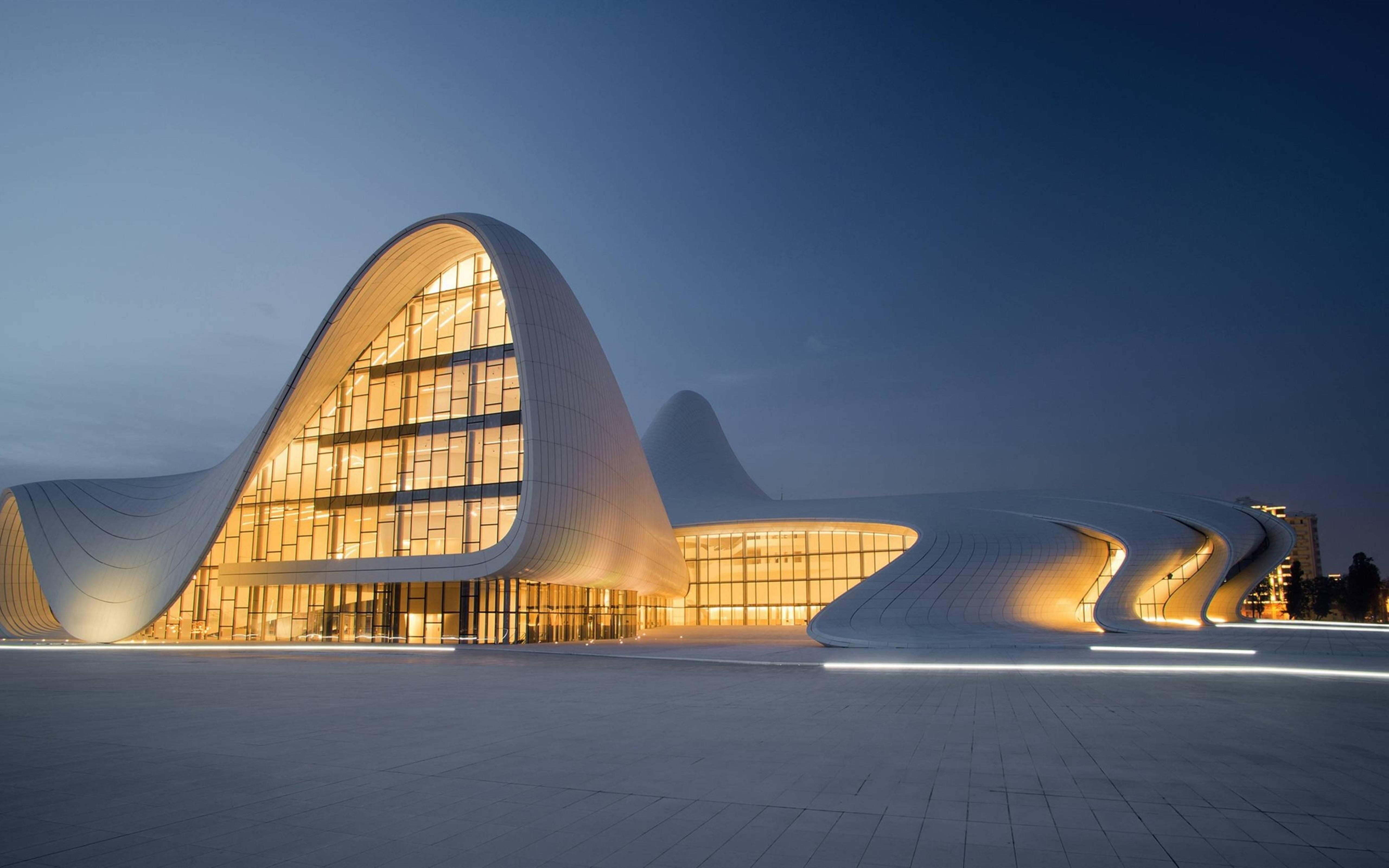 Architecture 桌布 壁紙 — 一座未來主義的白色建築，帶有發光的玻璃窗，在暮色天空中優雅地彎曲。