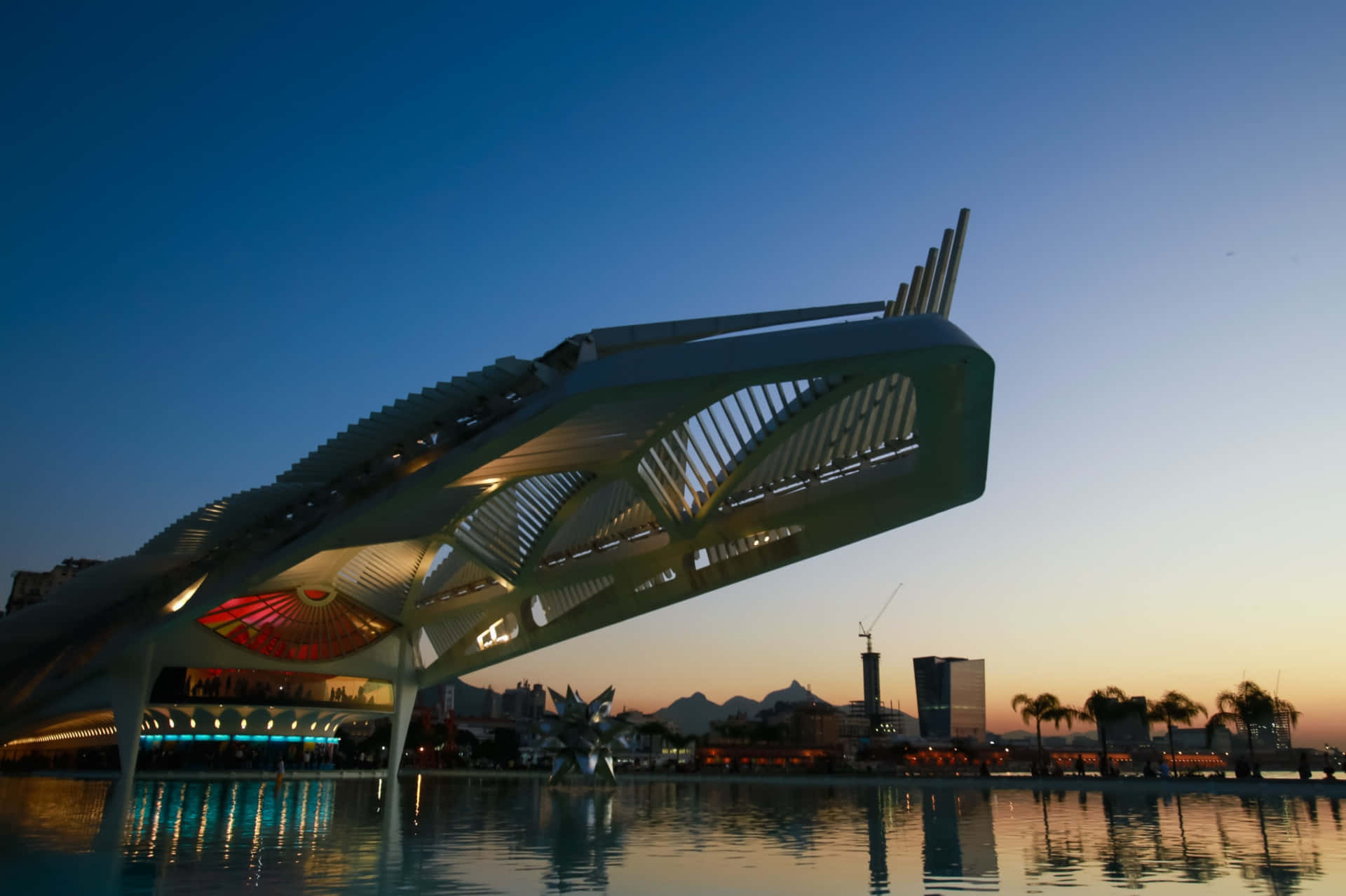 Beautiful Architecture 桌布 壁紙 — 一座未來主義風格的白色建築橋樑，內部發光的燈光在暮色中倒映在平靜的水面上。