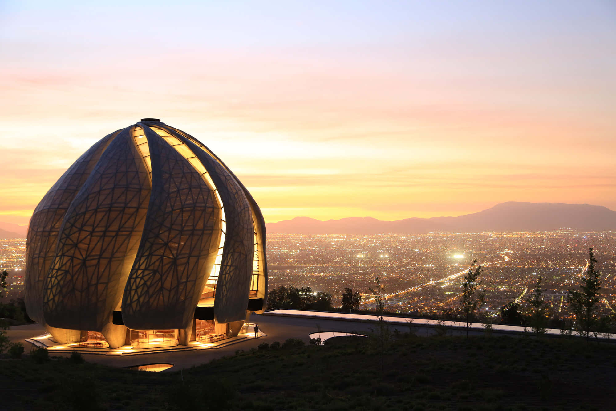 Beautiful Architecture 桌布 壁紙 — 一座未來風格的圓頂建築在日落時分於山頂上溫暖地發光，俯瞰著廣闊的城市。
