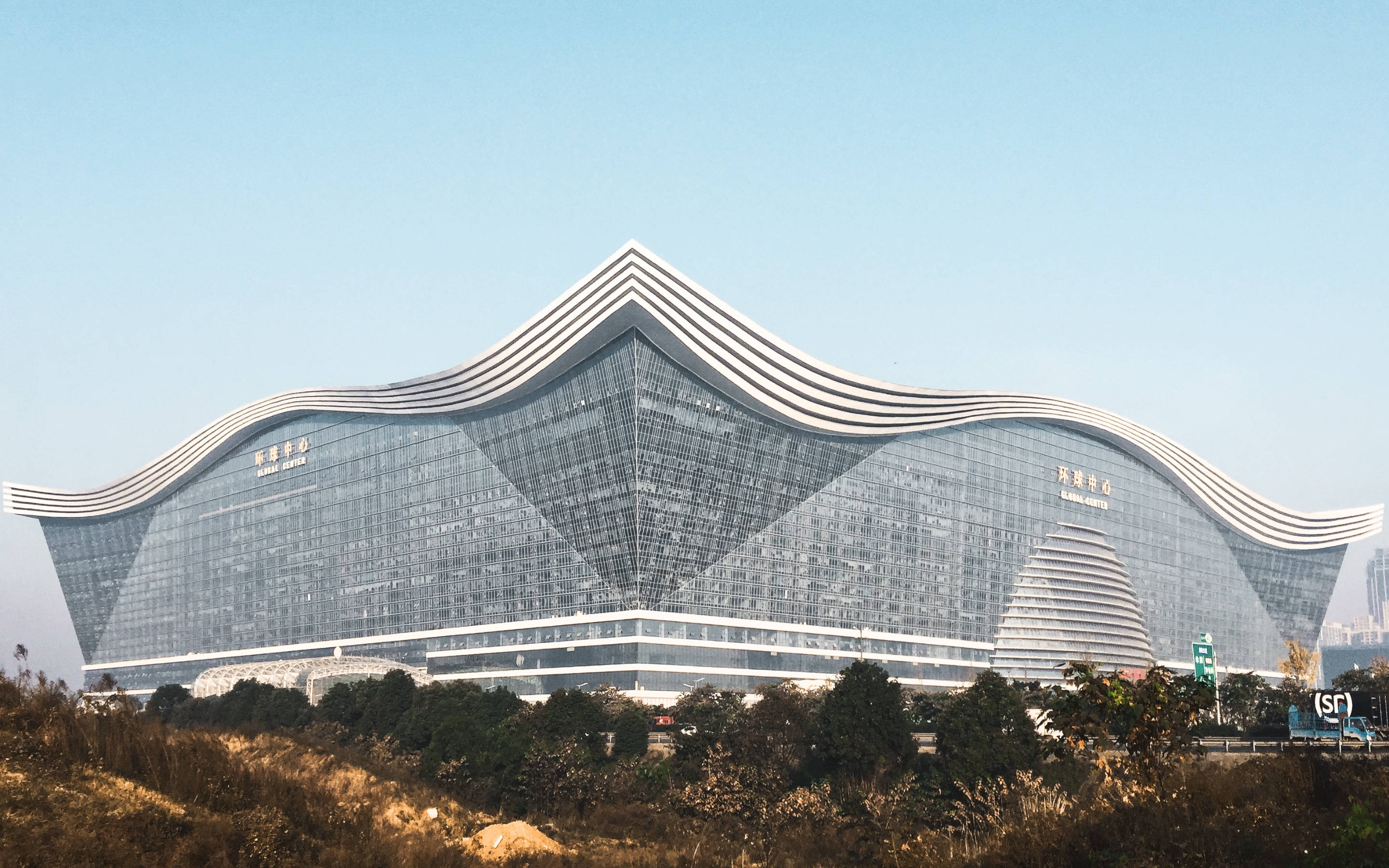 Chengdu 桌布 壁紙 — 一座未來風格的玻璃建築，帶有波浪狀白色條紋和弧形屋頂，在清澈的藍天下。