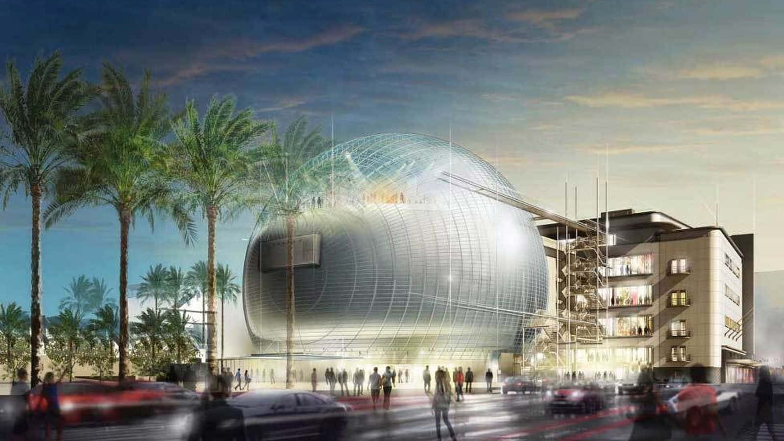 Architecture 桌布 壁紙 — 一座未來風格的銀色圓頂建築在黃昏中發光，周圍環繞著棕櫚樹和模糊的城市交通。