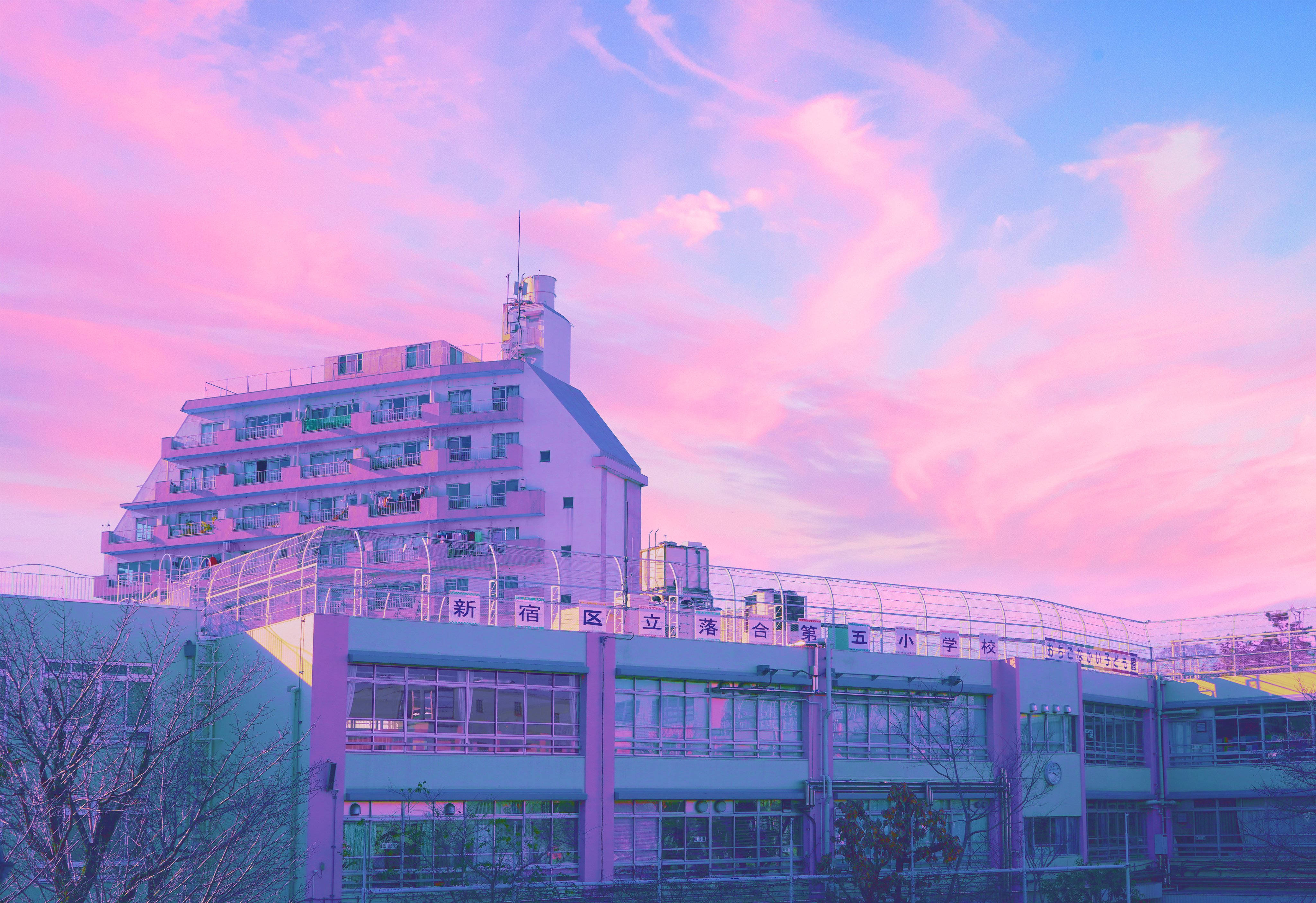 Japanese Aesthetic 桌布 壁紙 — 一座校舍沉浸在粉紅和紫色的暮色中，下方是夢幻的粉彩天空。