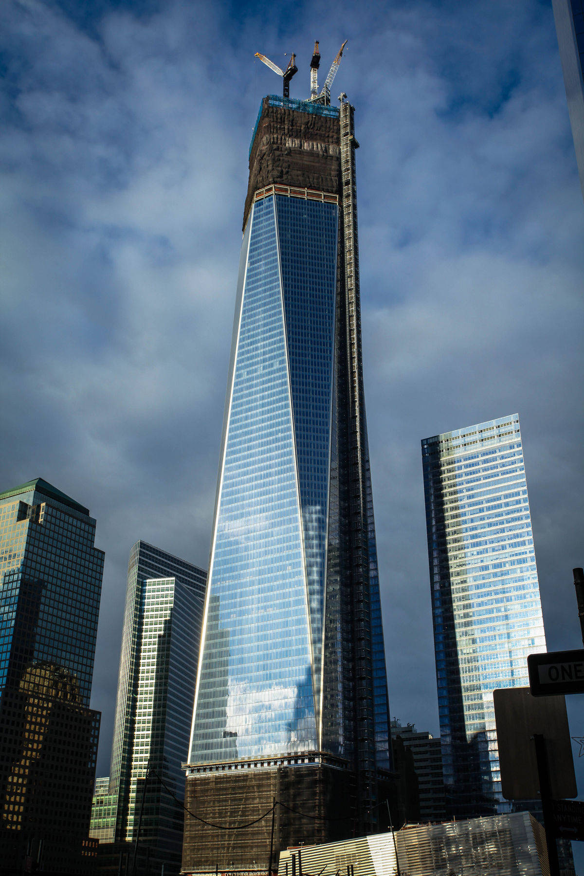 Building 桌布 壁紙 — 一座正在建造中的高聳摩天大樓，帶有反光玻璃外牆和起重機，背景是陰天。