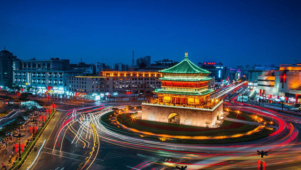 Xian 桌布 壁紙 — 一座歷史悠久的中國塔在黃昏時分溫暖地發光，汽車燈光在繁忙的城市圓環周圍旋轉。