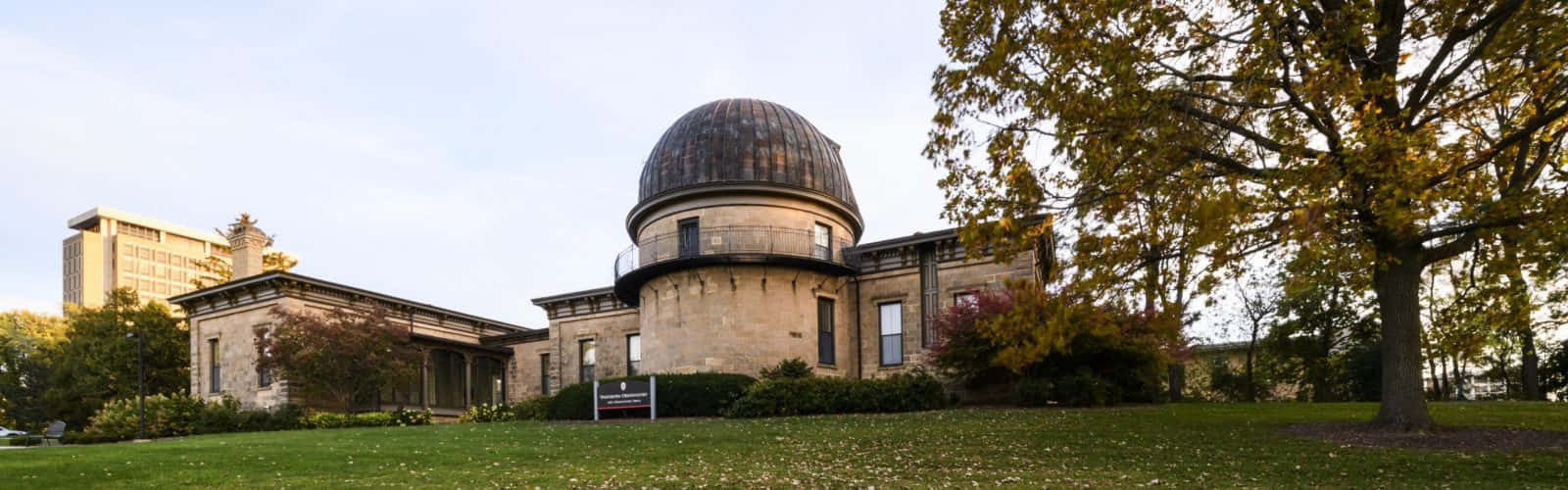 Observatory 桌布 壁紙 — 一座歷史悠久的石造天文台，帶有圓頂屋頂，矗立在秋天的樹木和綠色草坪之間，天空晴朗。