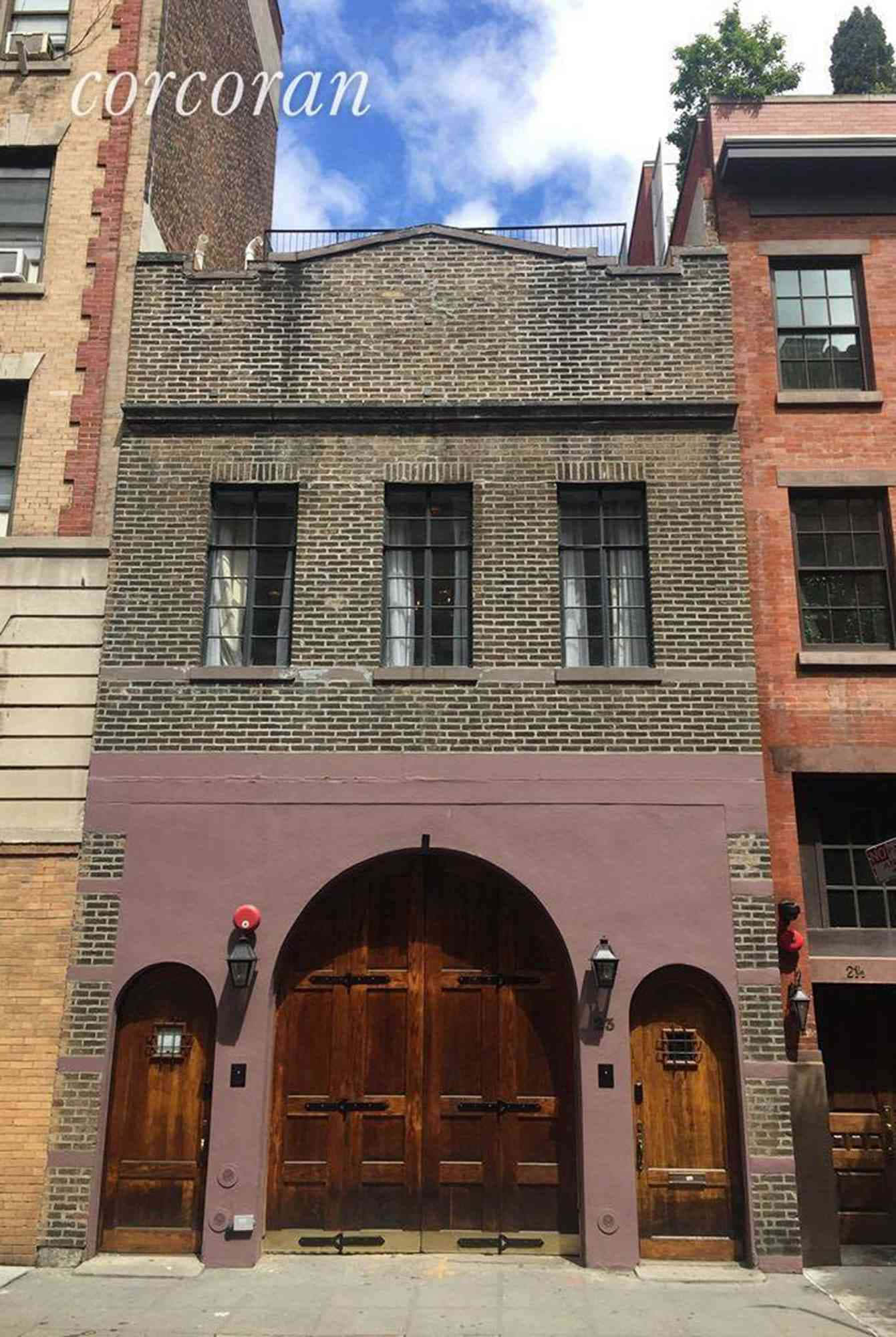 Street 桌布 壁紙 — 一座歷史悠久的磚造建築，在陽光明媚的日子裡，紫色外牆下有一個大型拱形木門和較小的側門。