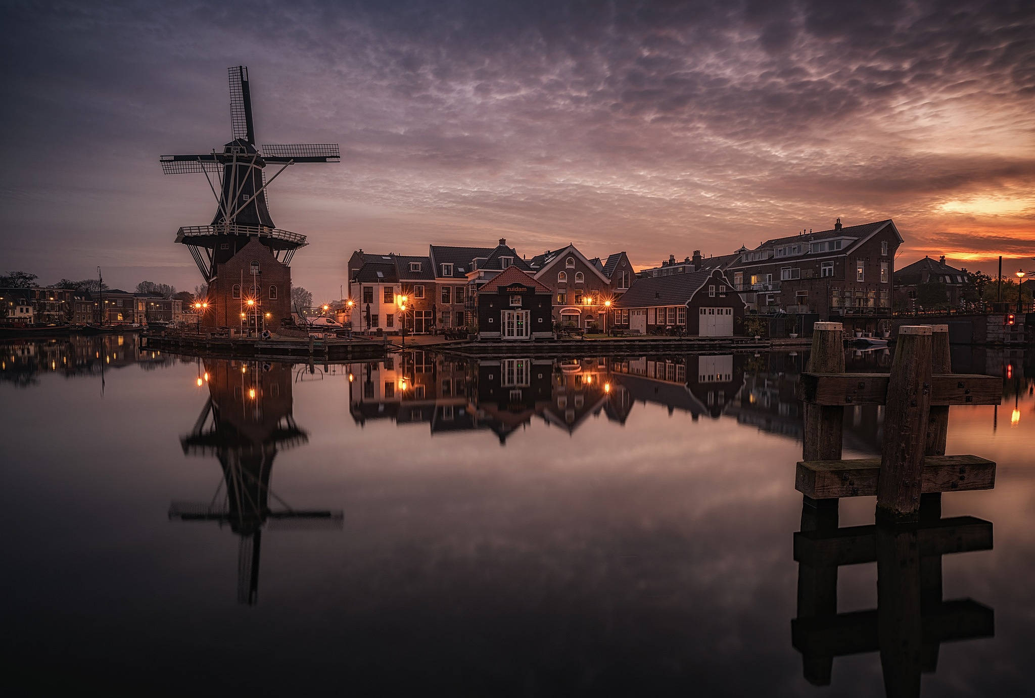 Netherlands 桌布 壁紙 — 一座歷史悠久的風車和運河邊的房屋在戲劇性的暮色天空下完美地倒映在平靜的水面上。