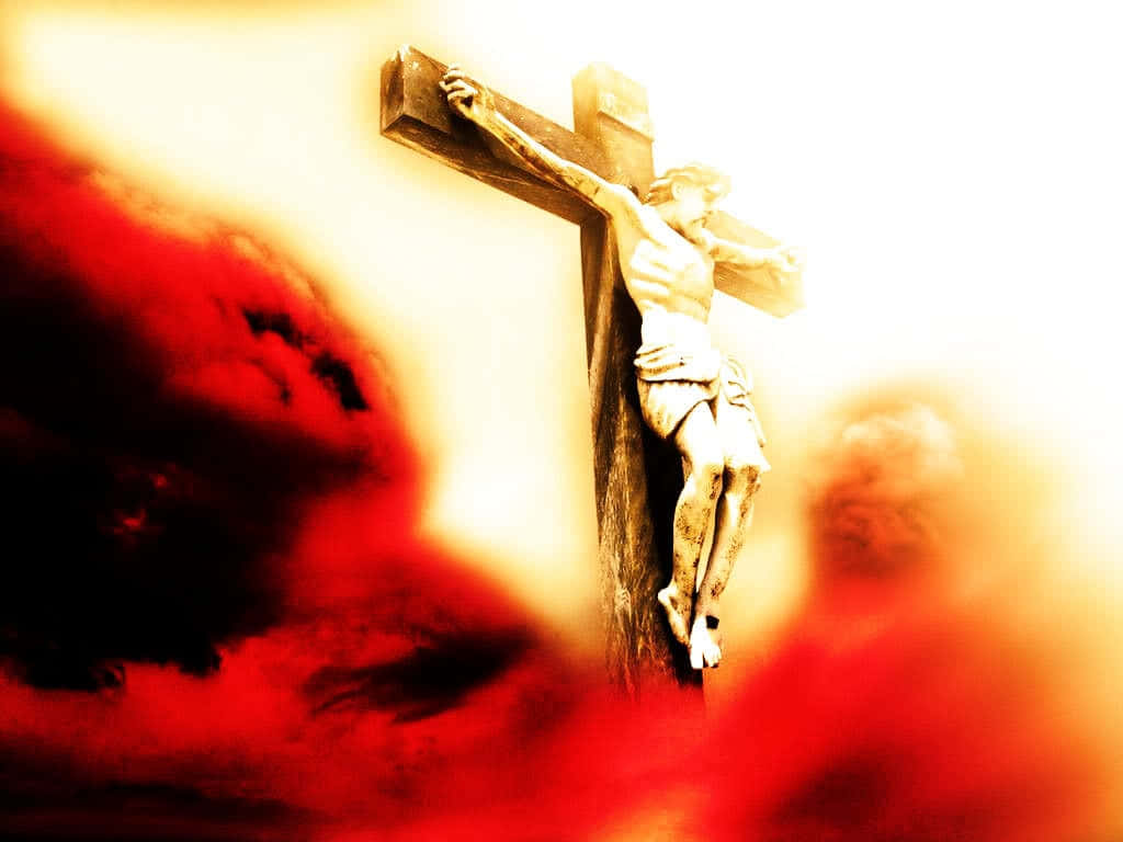 Jesus Crucifixion 桌布 壁紙 — 一座沐浴在金色光芒中的 crucifixion 雕像，前景有戲劇性的紅色雲彩翻騰。