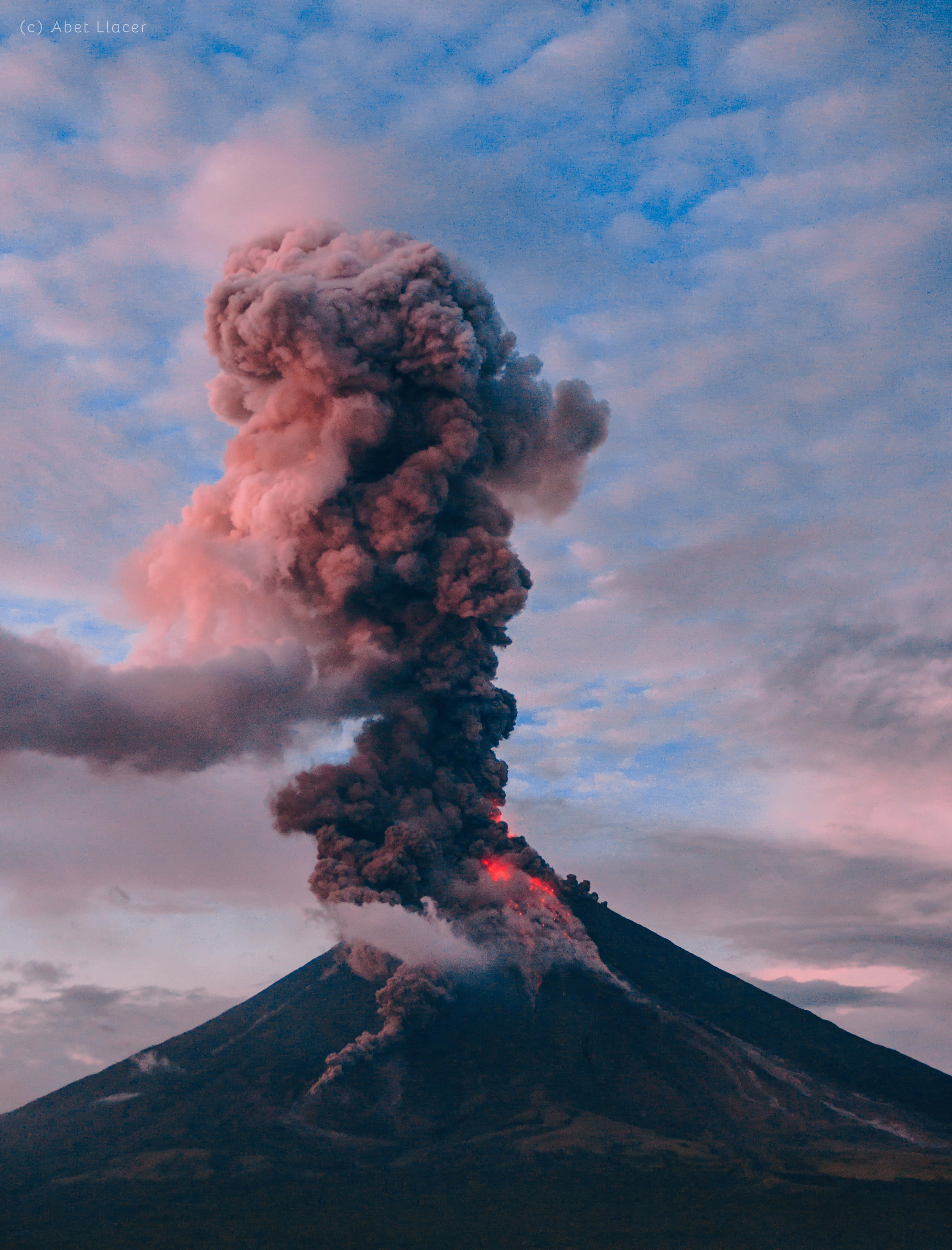 Volcano 桌布 壁紙 — 一座火山在黃昏時猛烈噴發，將發光的熔岩和濃煙噴向粉紅色和藍色的天空。