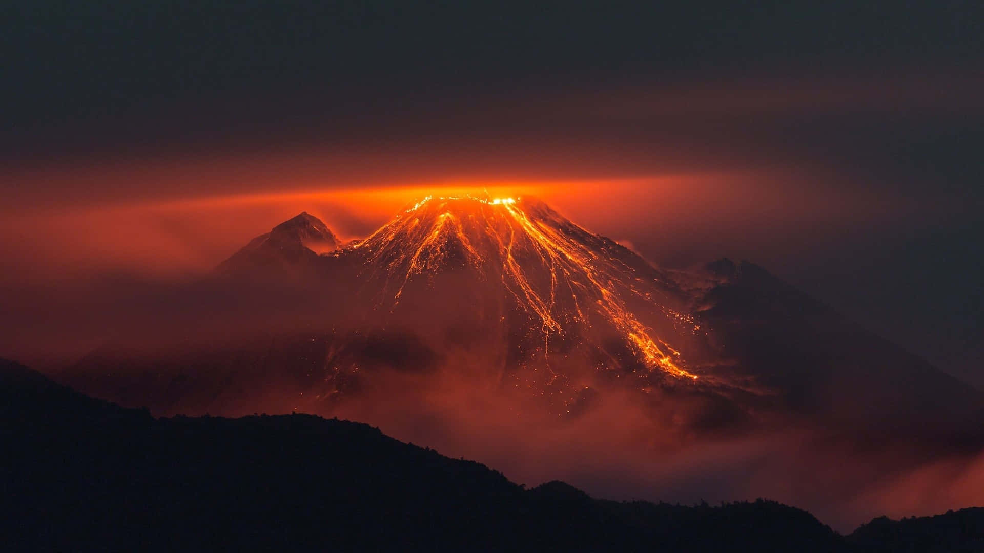 山景 桌布 壁紙 — 一座火山爆發，發光的熔岩沿著山坡流下，映襯著黑暗的天空。