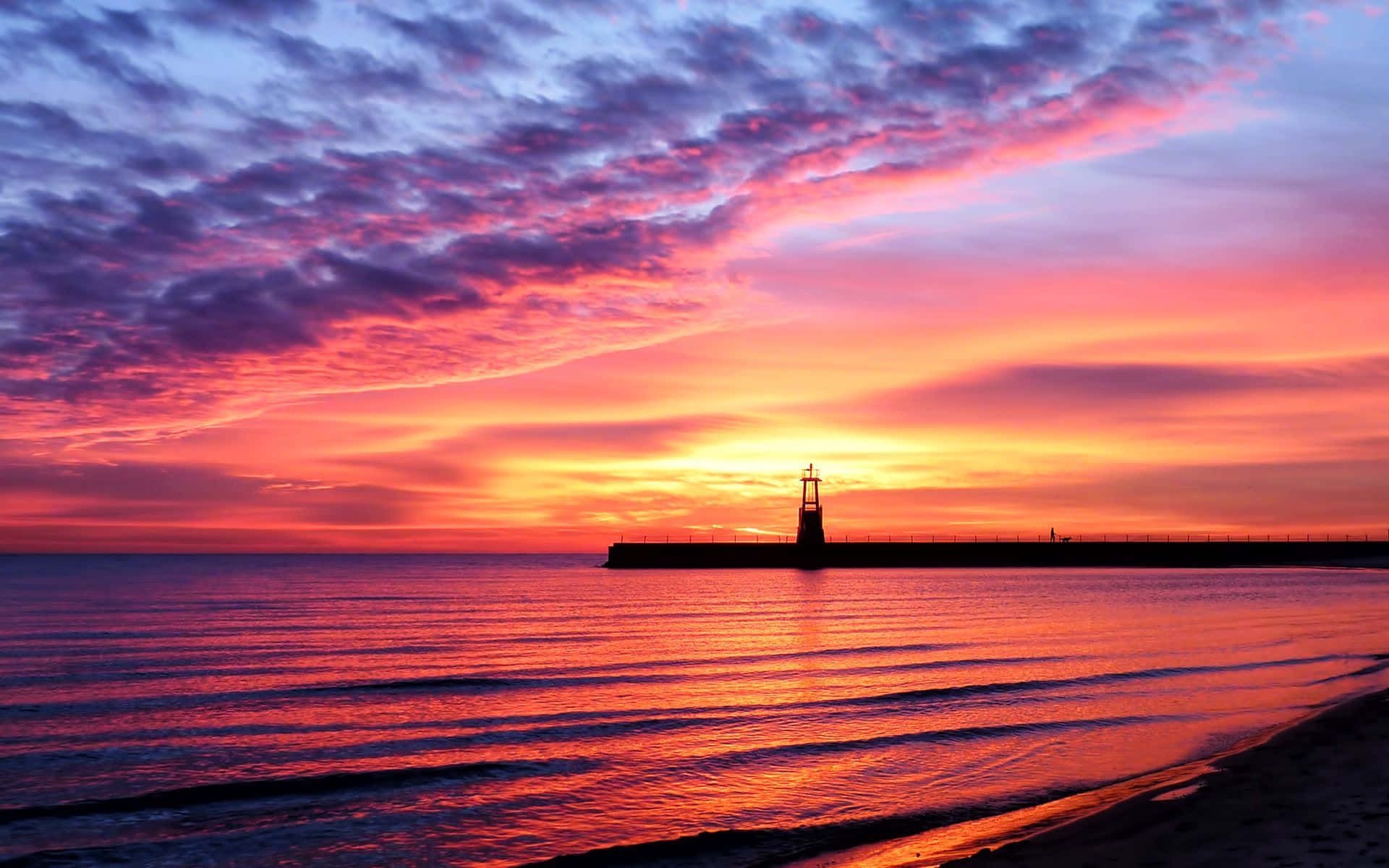 Sunset Photography 桌布 壁紙 — 一座燈塔在平靜的海面上，映襯著火燒般的夕陽天空，形成剪影。