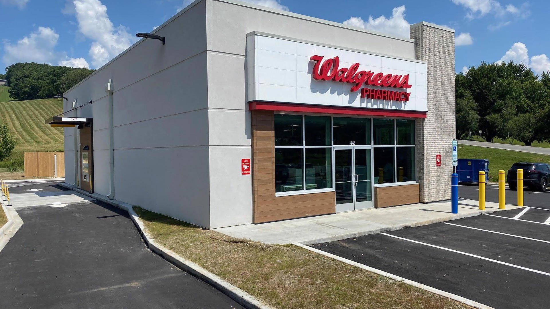 Business 桌布 壁紙 — 一座現代化的Walgreens藥房建築，帶有紅色標牌，矗立在晴朗的藍天和白雲下。