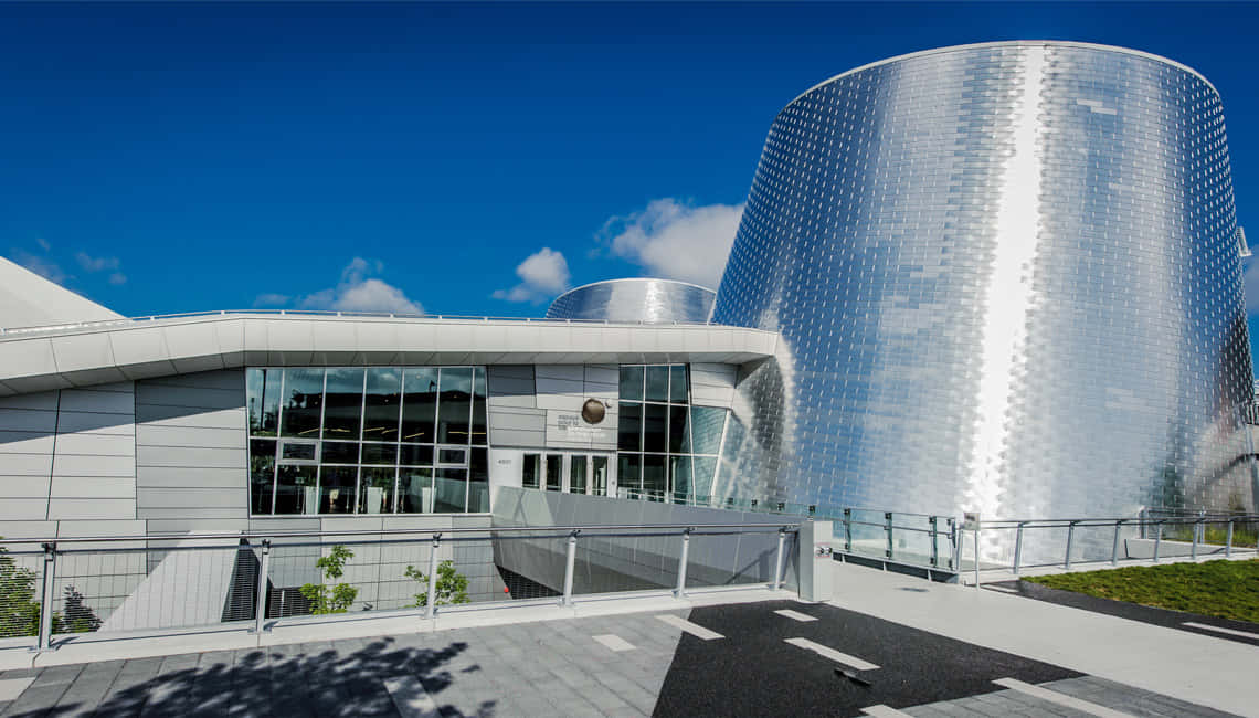 Planetarium 桌布 壁紙 — 一座現代建築奇蹟，擁有閃閃發光的銀色圓柱形塔樓和玻璃外牆，在清澈的藍天下。