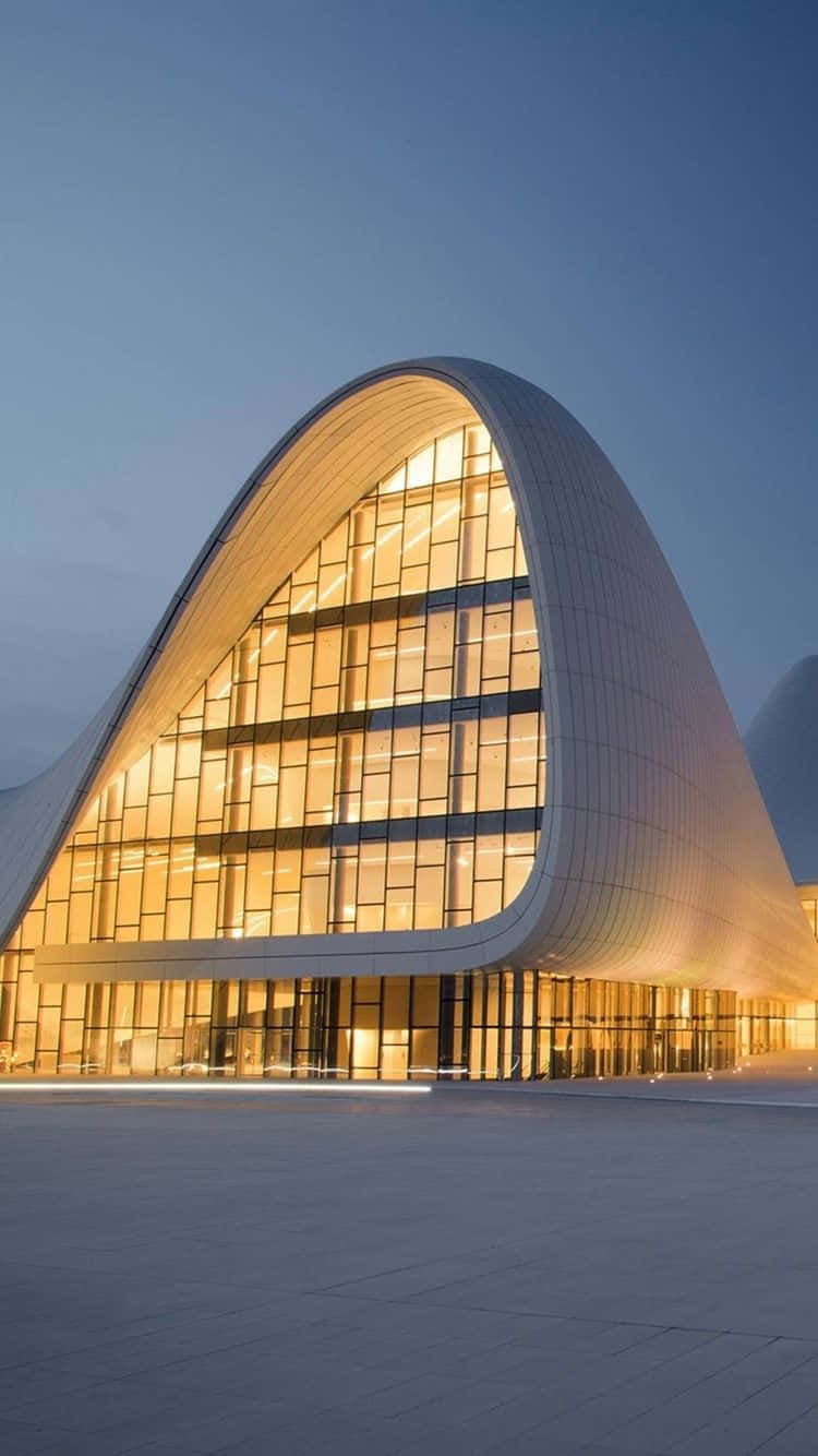 Modern Aesthetic 桌布 壁紙 — 一座現代弧形玻璃建築在暮色天空下溫暖發光，搭配光滑的混凝土廣場。