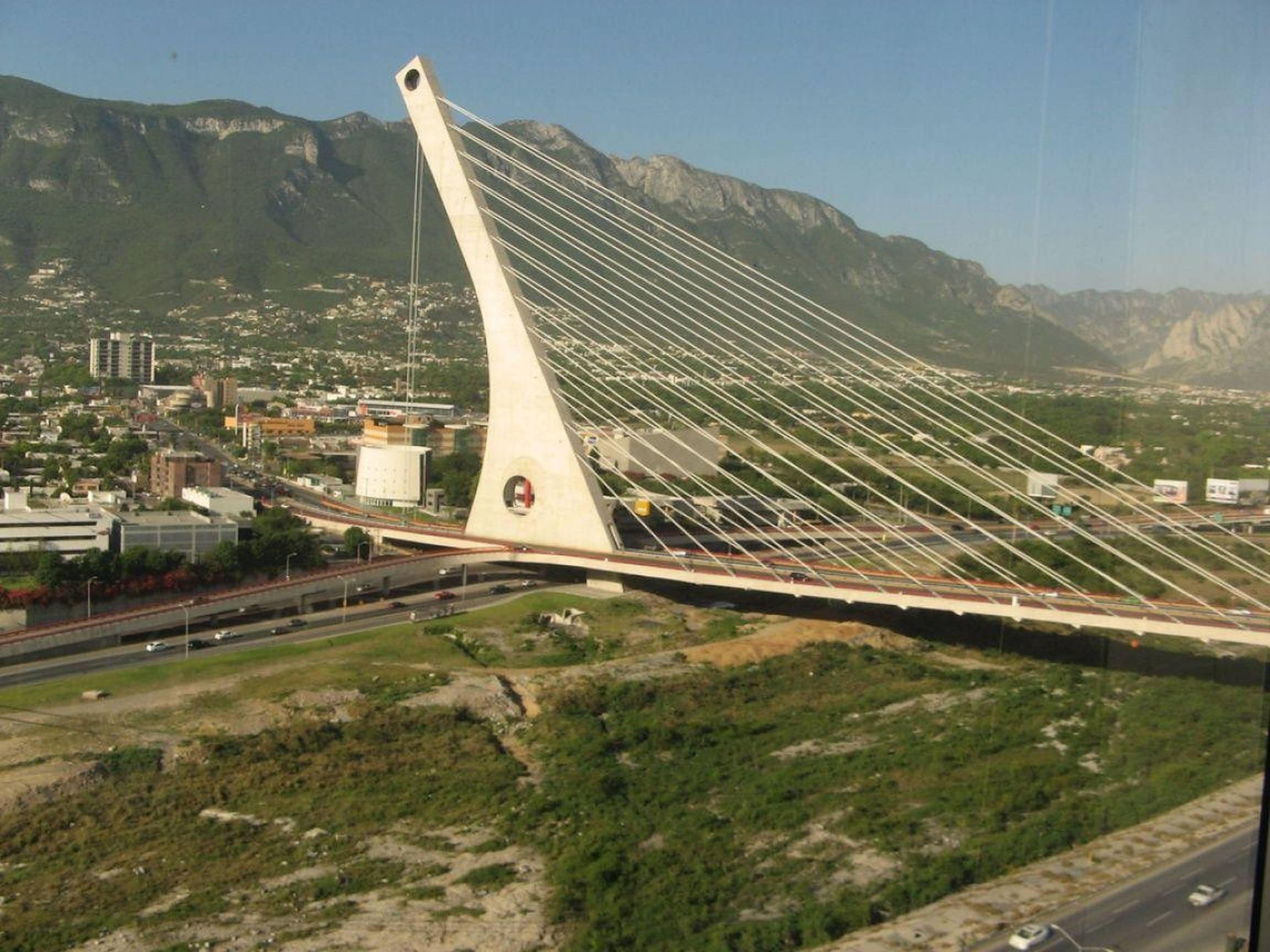 Monterrey 桌布 壁紙 — 一座現代斜張橋橫跨山谷，背景是山脈，天空湛藍清澈。