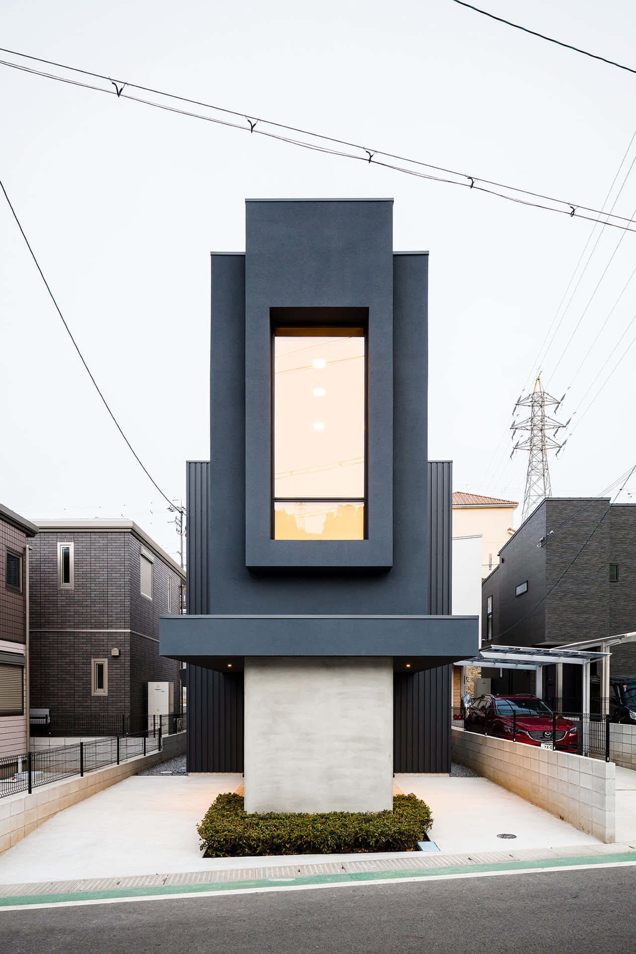 Minimalist Architecture 桌布 壁紙 — 一座現代黑色房屋，帶有發光的垂直窗戶，矗立在寧靜城市社區的混凝土底座上。