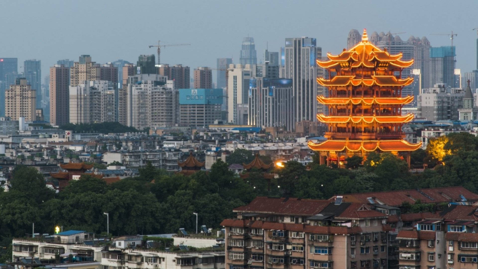 Wuhan 桌布 壁紙 — 一座發光的傳統中式寶塔在黃昏時分的現代城市天際線中脫穎而出。
