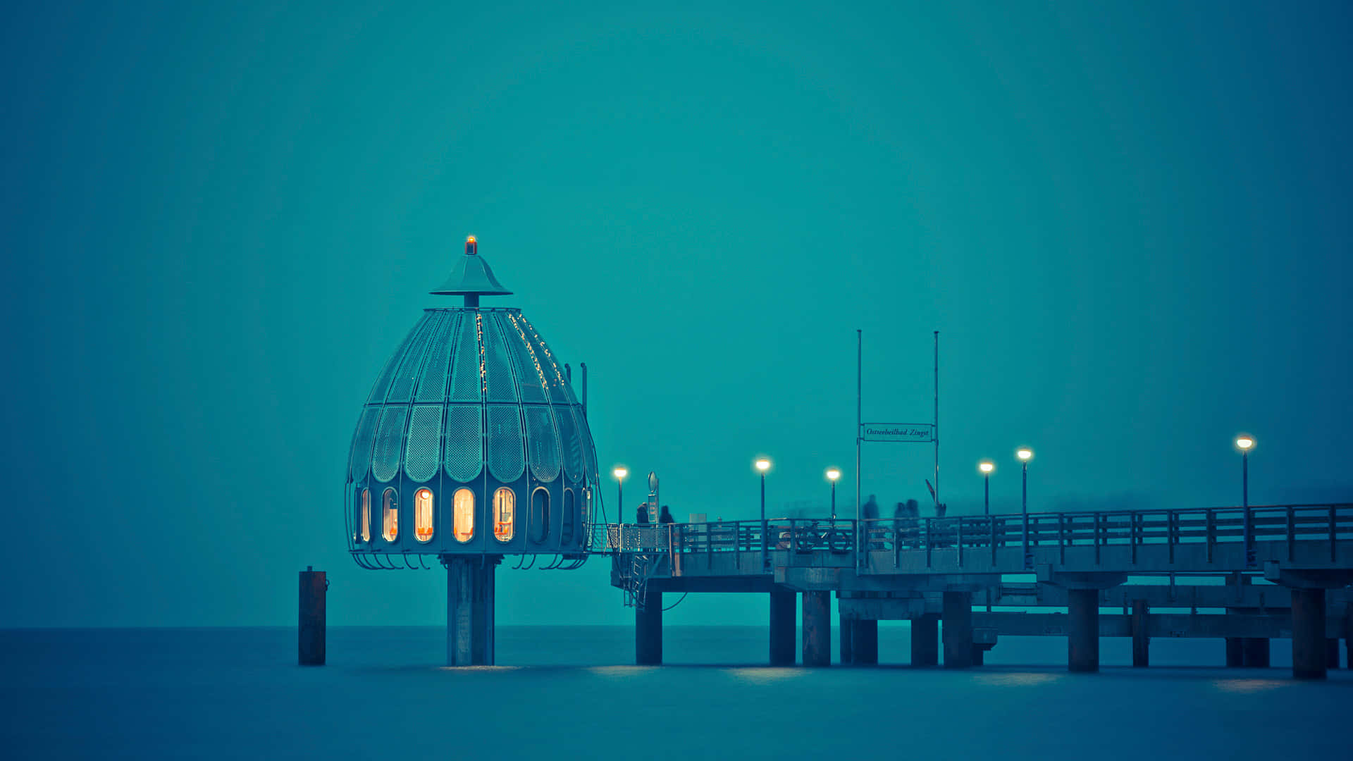 Harbor 桌布 壁紙 — 一座發光的玻璃圓頂結構矗立在碼頭盡頭，在青綠色的暮色天空下，溫暖的燈光照亮平靜的水面。