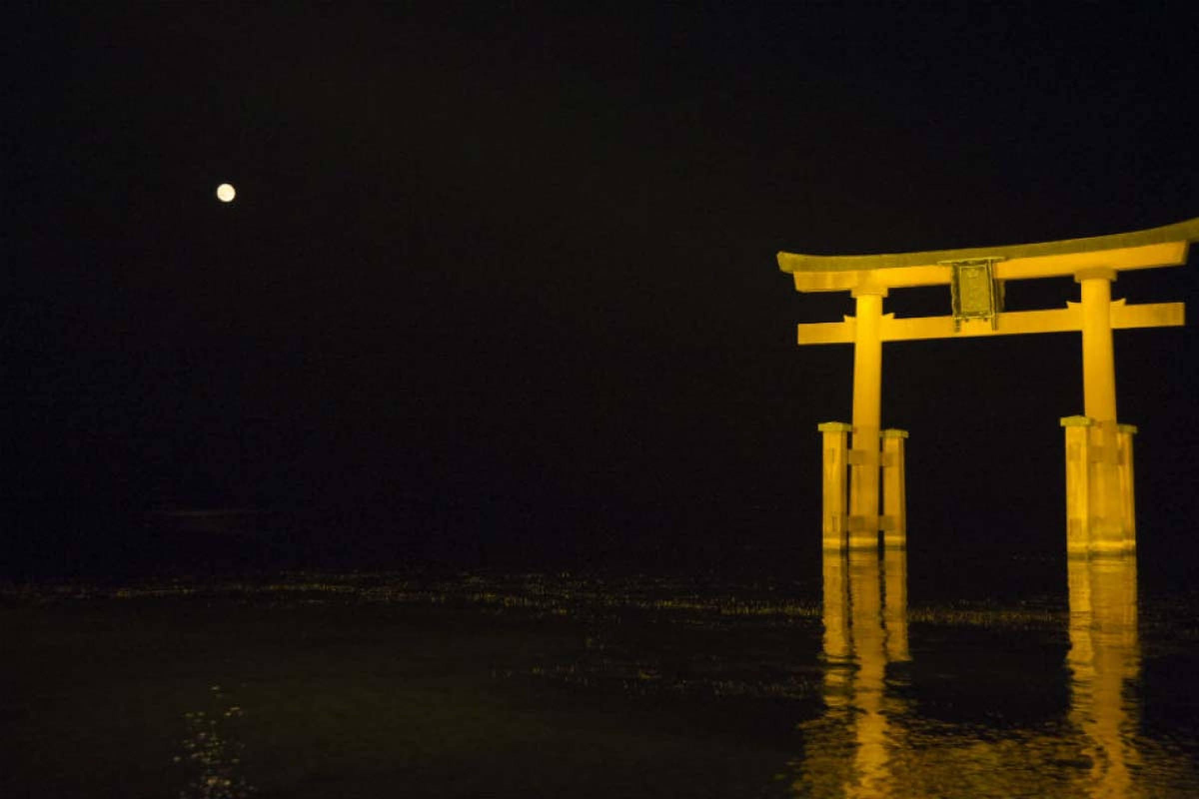 Torii 桌布 壁紙 — 一座發光的黃色鳥居矗立在黑暗的水中，明亮的月亮投下寧靜的倒影。