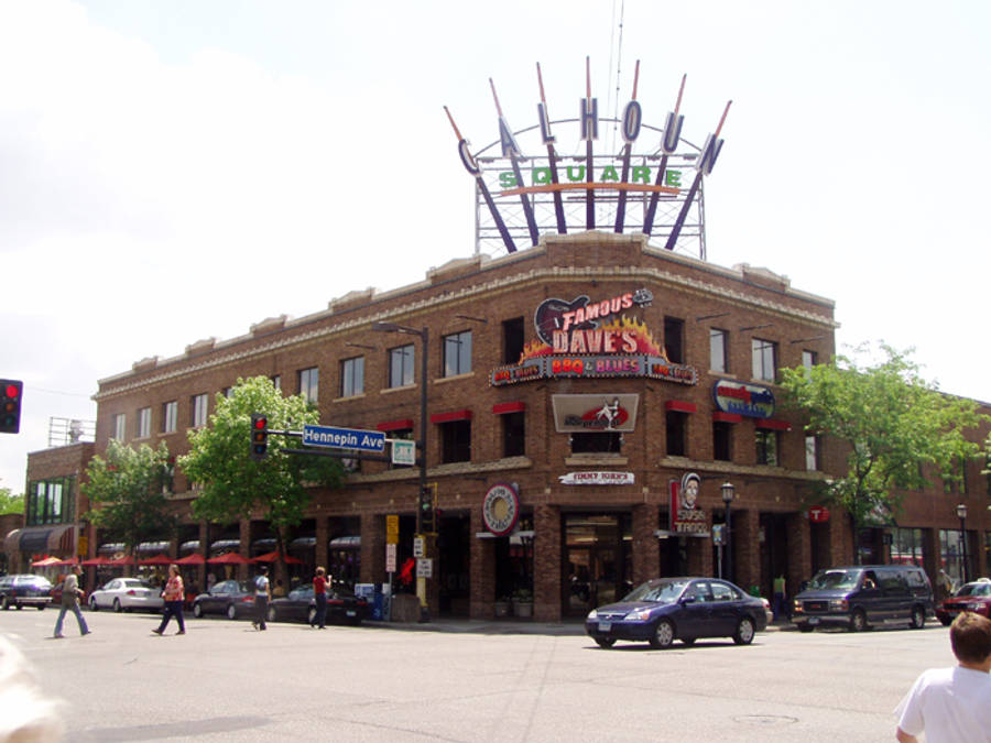 Minneapolis 桌布 壁紙 — 一座磚砌建築，帶有大型「CALHOUN SQUARE」標誌和「FAMOUS DAVE'S」餐廳標誌，矗立在街角，有汽車和行人，天空明亮。