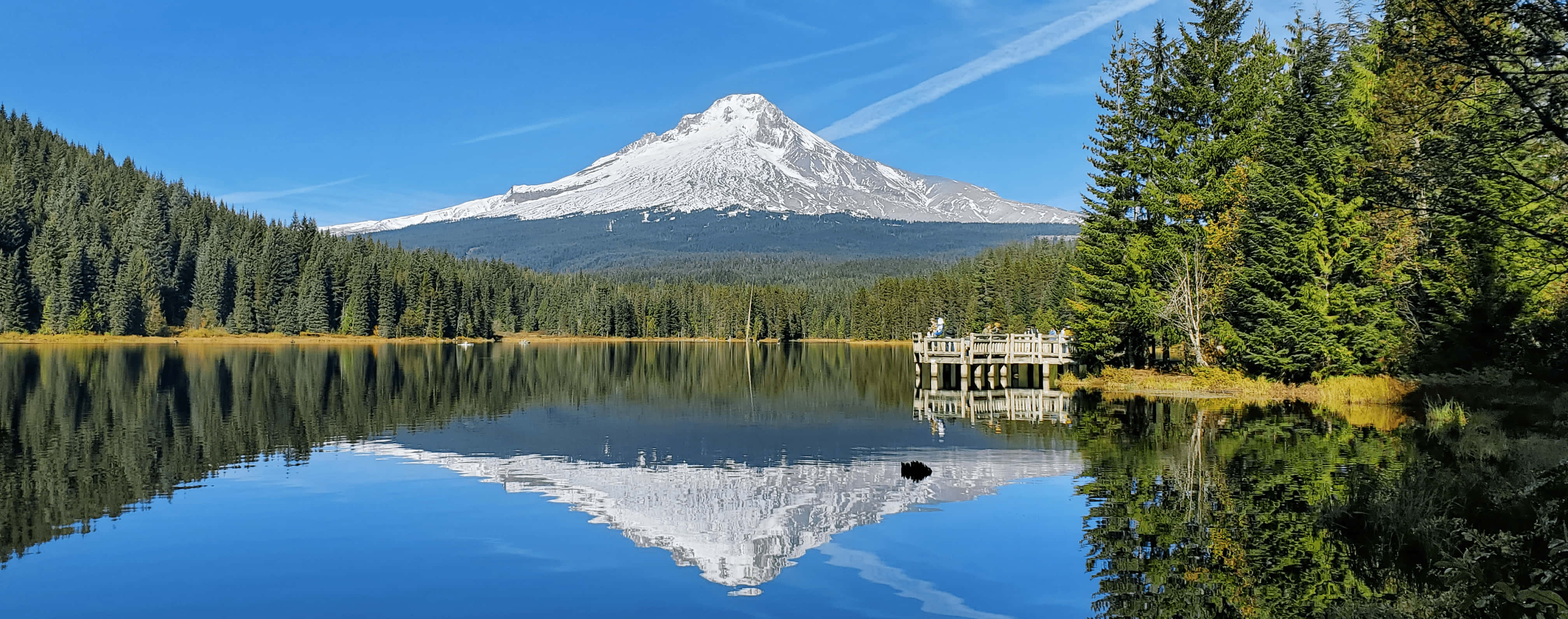 Mount Hood 桌布 壁紙 — 一座積雪的山峰在平靜的湖泊後方升起，倒映著山頂和周圍的常綠森林，天空清澈湛藍。