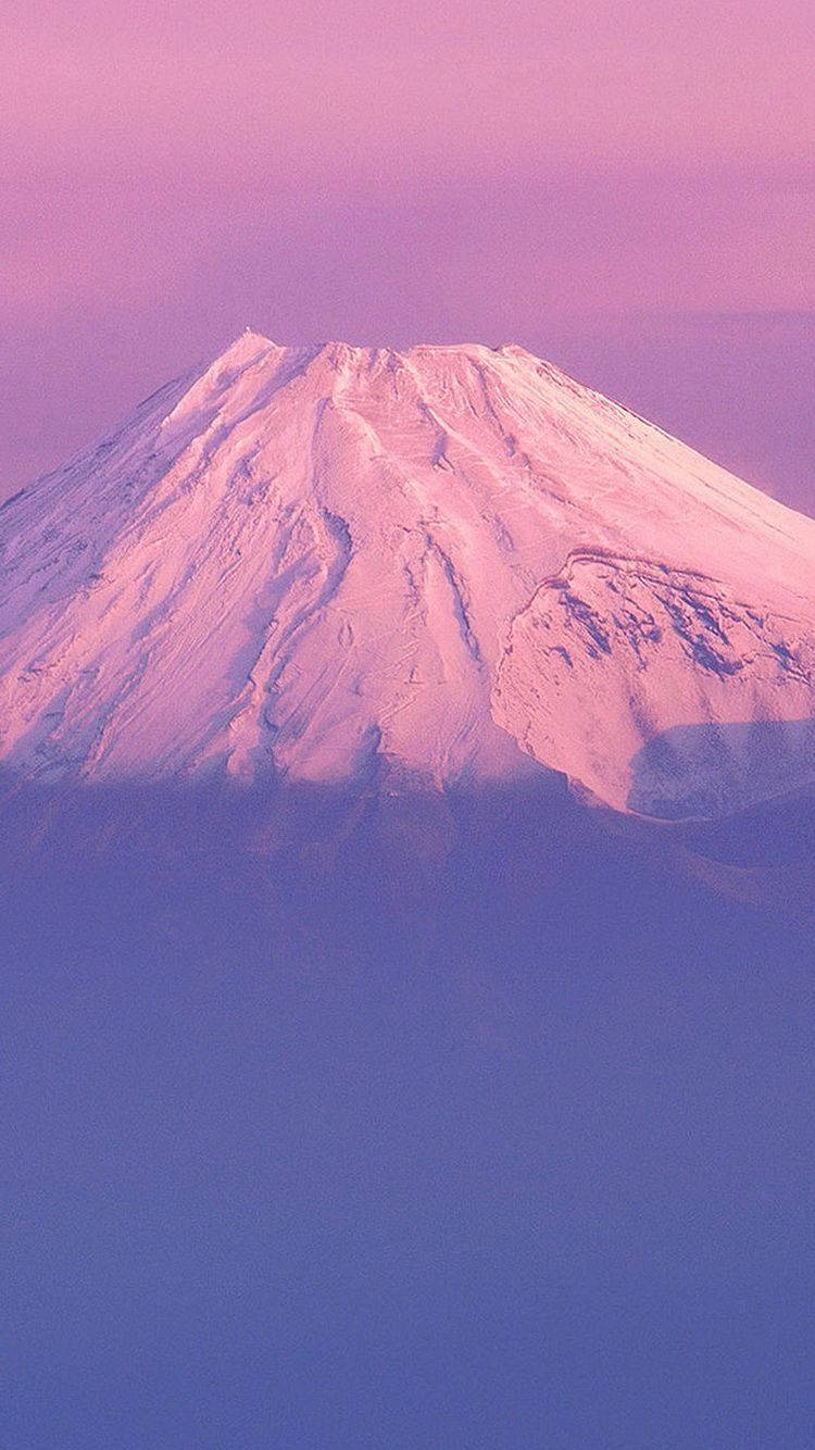 粉嫩美學 iPhone 桌布 壁紙 — 一座積雪的山峰在漸變色的天空下沐浴在柔和的粉紅色和紫色暮色中。
