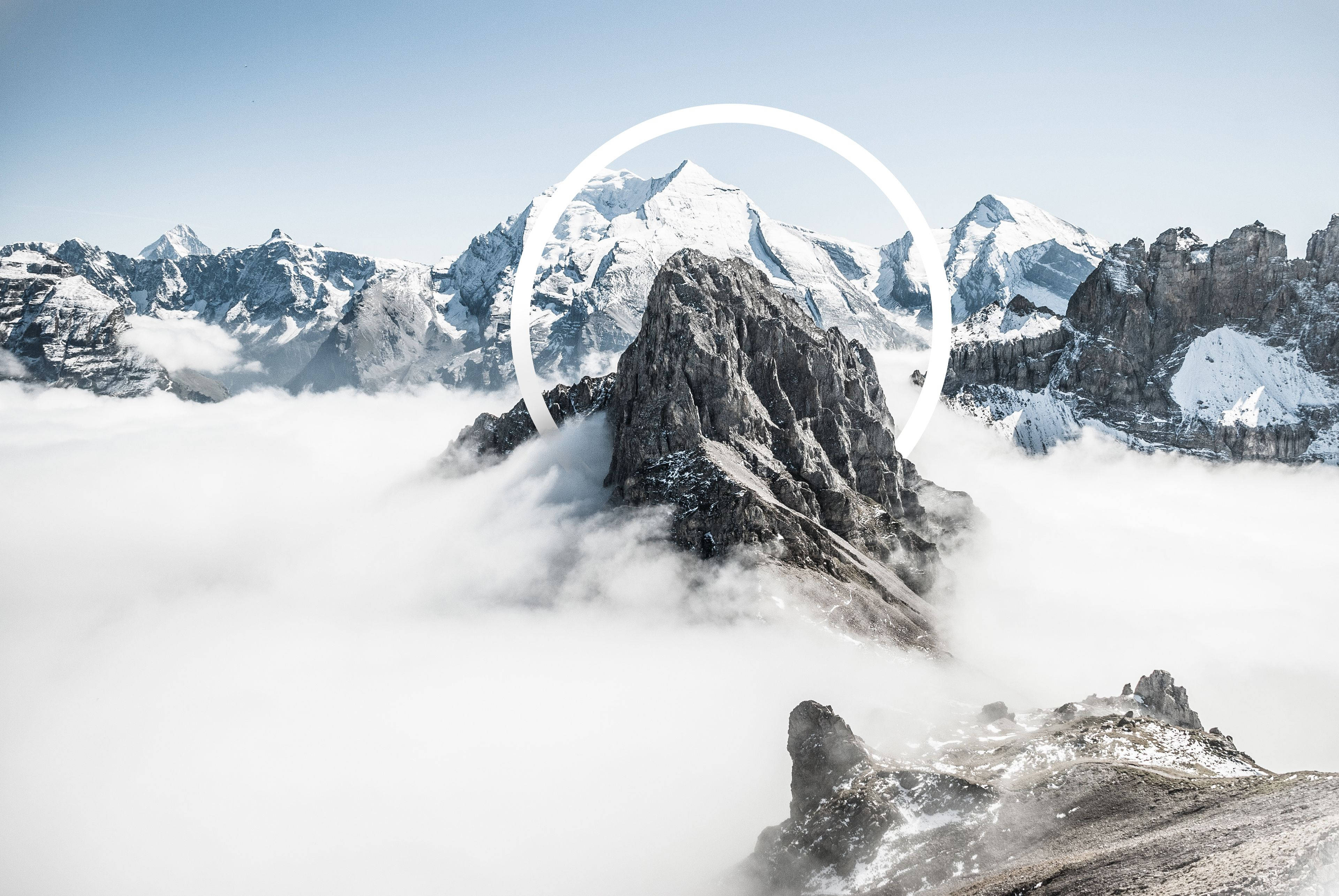 雲朵 桌布 壁紙 — 一座積雪的山峰聳立在雲海之上，白色圓形圖案框住其山頂。