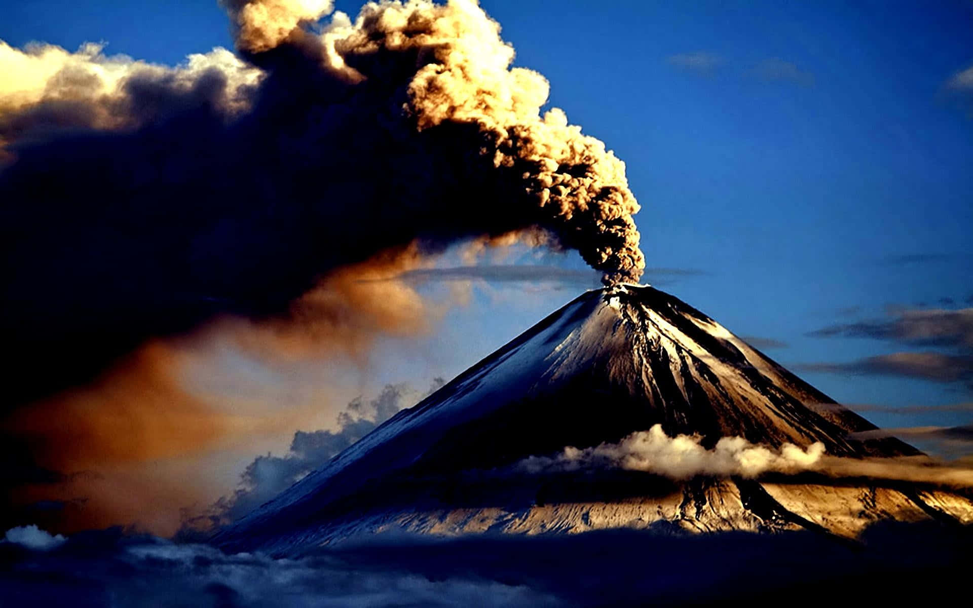 山景 桌布 壁紙 — 一座積雪覆蓋的火山猛烈噴發，將濃煙送入戲劇性的暮色天空。