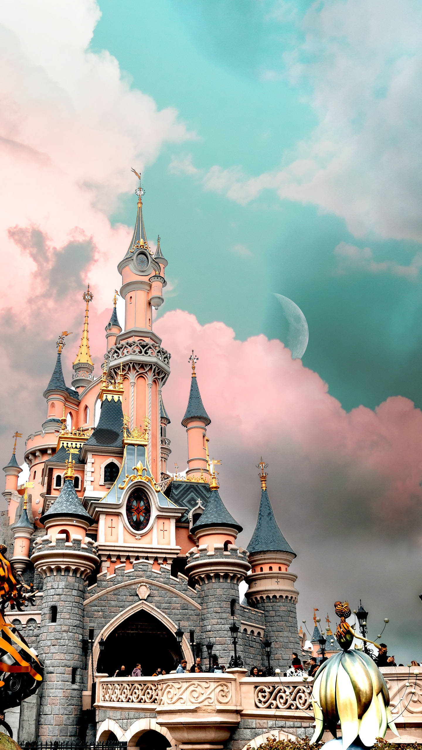 城堡動畫 桌布 壁紙 — 一座童話城堡，擁有粉紅色塔樓和藍色屋頂，矗立在夢幻般的天空下，天空中有粉紅色的雲朵和一彎新月。