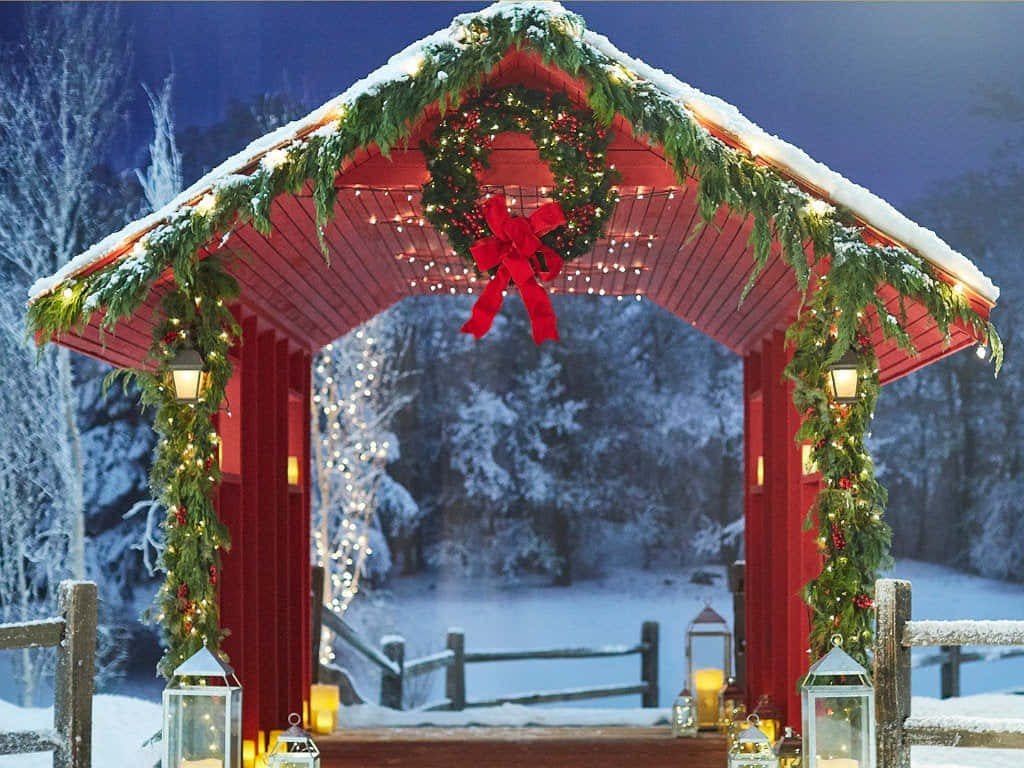 Christmas Decor 桌布 壁紙 — 一座節日氣氛的紅色木橋，覆蓋著白雪，並以發光的花環和燈串裝飾，映襯著雪夜的冬夜。
