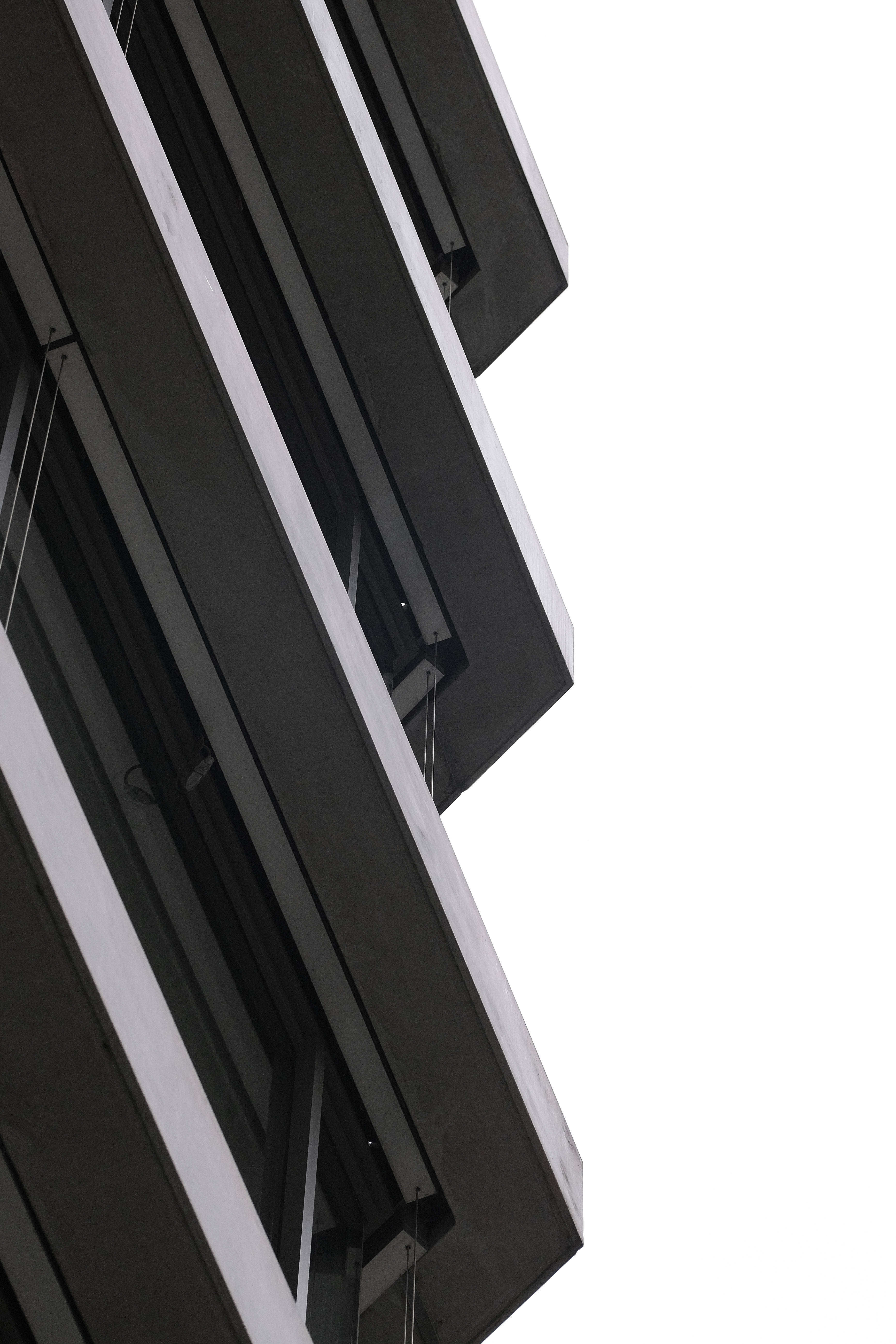 Dark 4K 桌布 壁紙 — 一座簡約現代建築的外牆，以大膽的黑白幾何線條向上傾斜，映襯著明亮的白色天空。