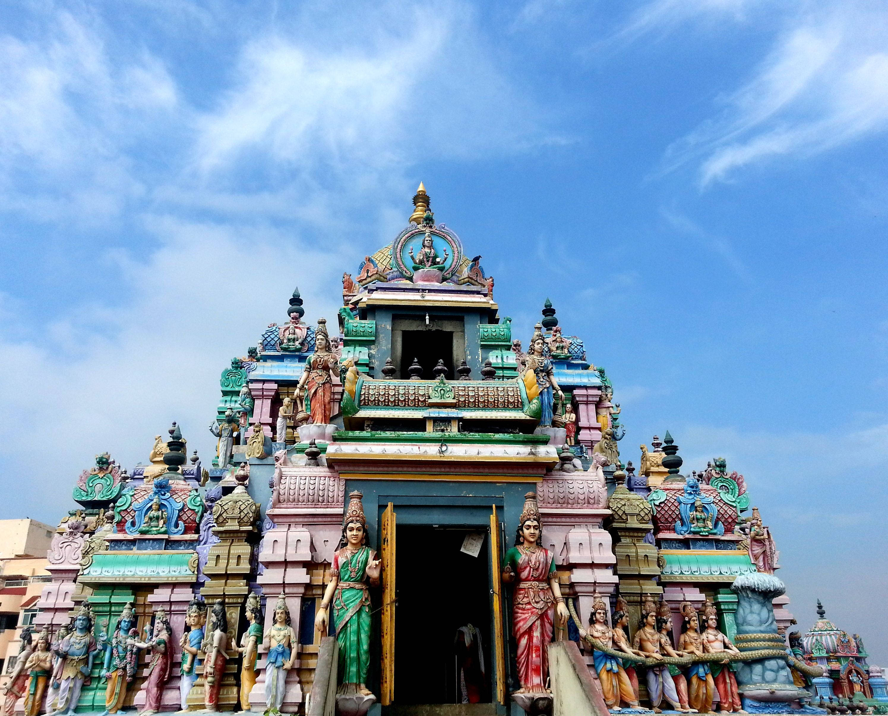 Chennai 桌布 壁紙 — 一座色彩繽紛、雕刻精細的印度教寺廟外牆，在明亮藍天和薄雲下裝飾著多彩雕像。