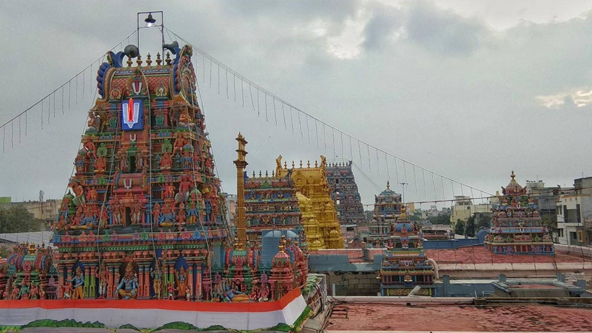 Chennai 桌布 壁紙 — 一座色彩繽紛、雕刻精緻的寺廟塔門（gopuram）在陰天的城市環境中聳立。