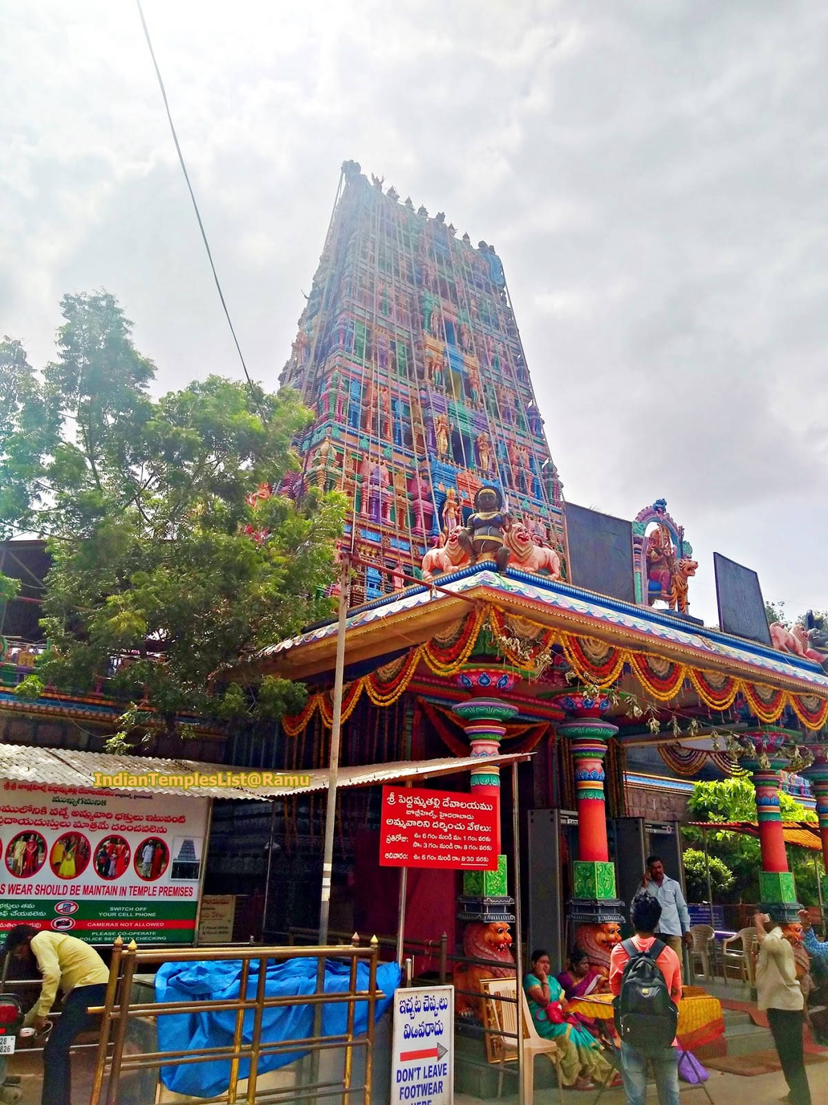 Hyderabad 桌布 壁紙 — 一座色彩繽紛的印度教寺廟高塔聳立在熙來攘往的入口上方，信眾和茂密的綠樹在陰天之下。