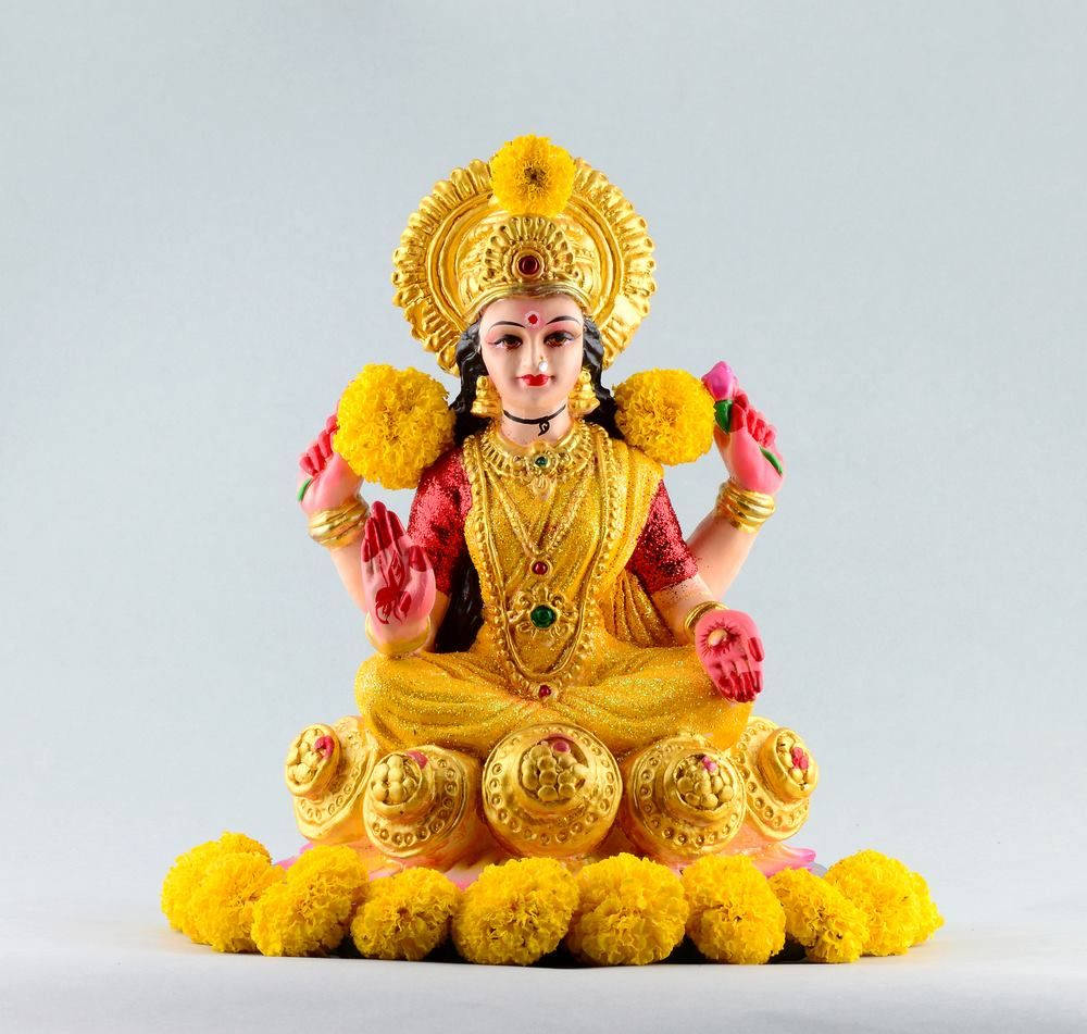 金色印度教女神雕像，周圍環繞著萬壽菊和珠寶。 — 拉克什米女神 壁紙