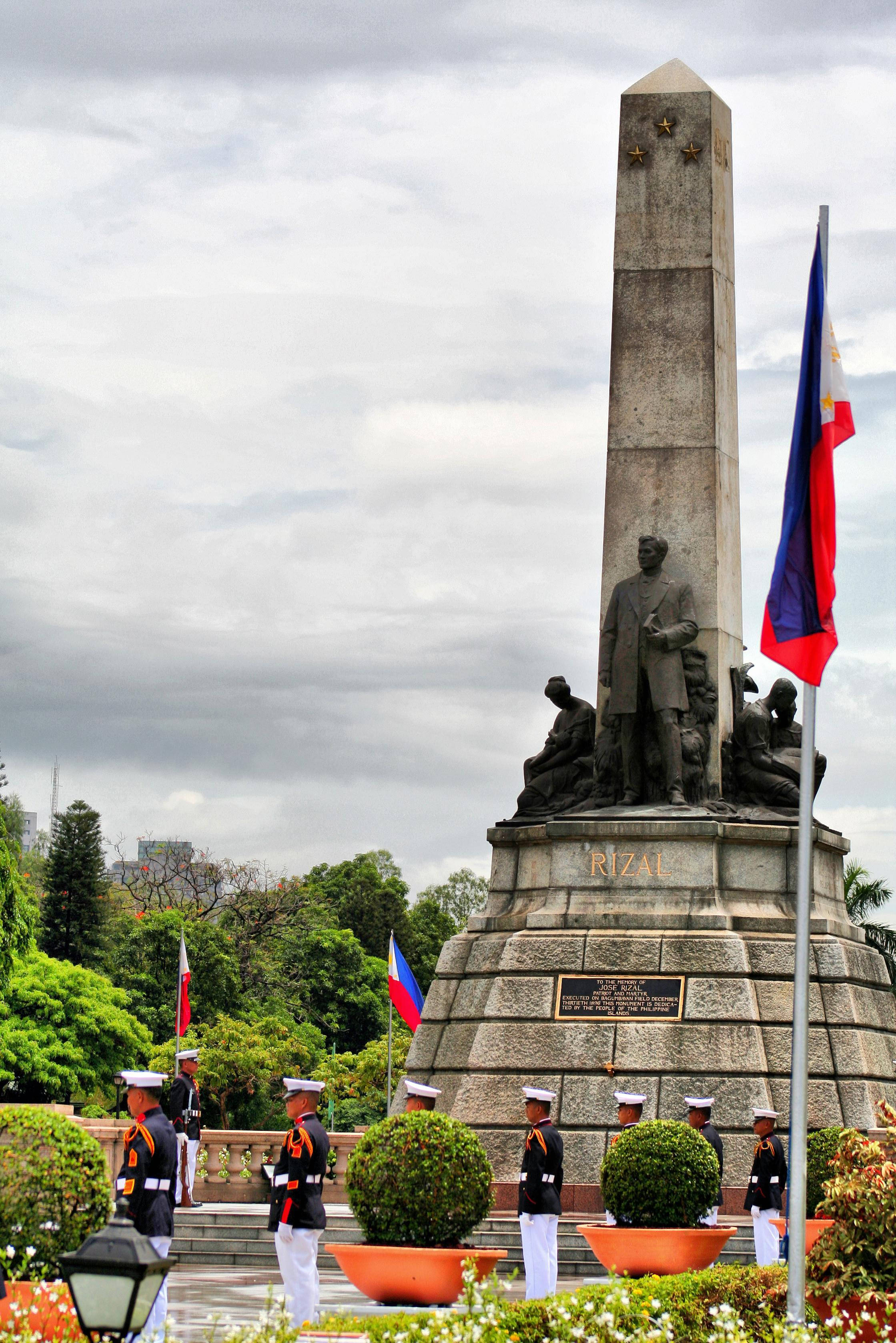 Manila 桌布 壁紙 — 一座莊嚴的黎剎石像紀念碑矗立在陰天之下，底部有身穿制服的衛兵和菲律賓國旗。