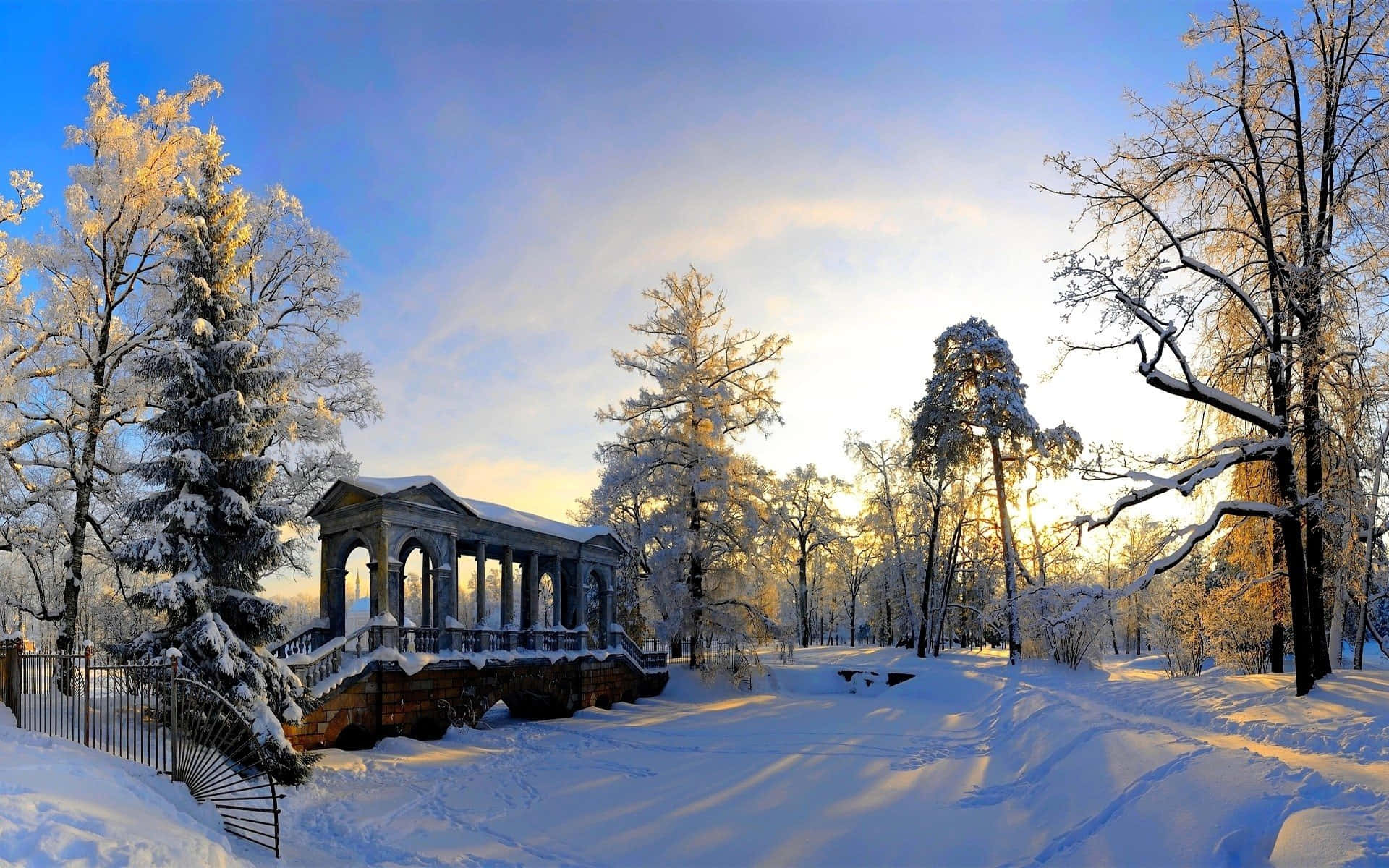 Winter Scenery Desktop 桌布 壁紙 — 一座被雪覆蓋的古典亭閣，沐浴在金色日出光芒中，周圍是掛滿霜雪的樹木，位於寧靜的冬季公園。