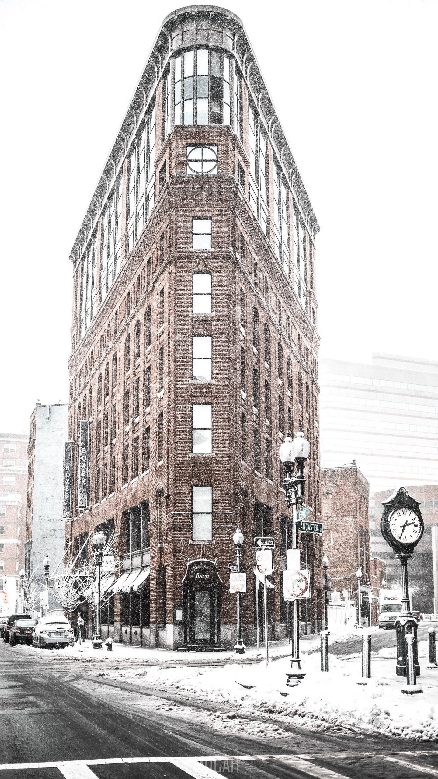 Building 桌布 壁紙 — 一座被雪覆蓋的磚角建築矗立在寧靜的冬季城市街道上，配有復古路燈和時鐘。