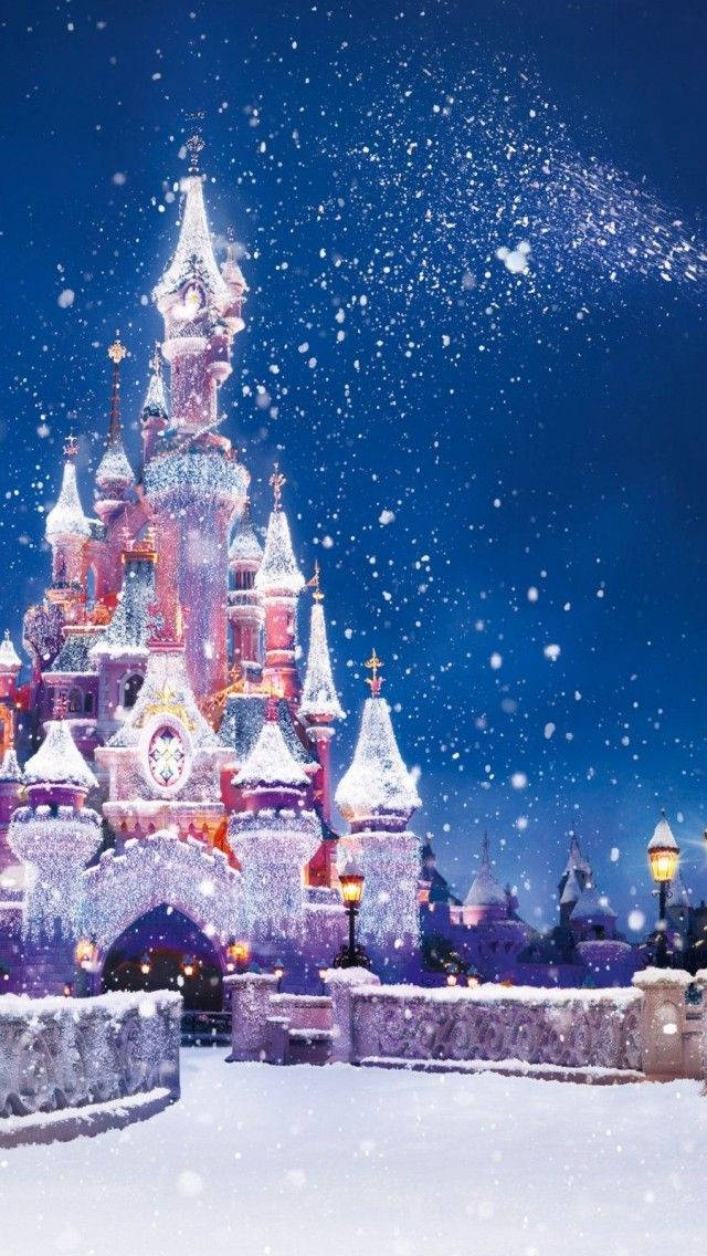 Disney Castle 桌布 壁紙 — 一座被雪覆蓋的雄偉城堡在星空下閃耀著節日燈光，雪花輕輕飄落。