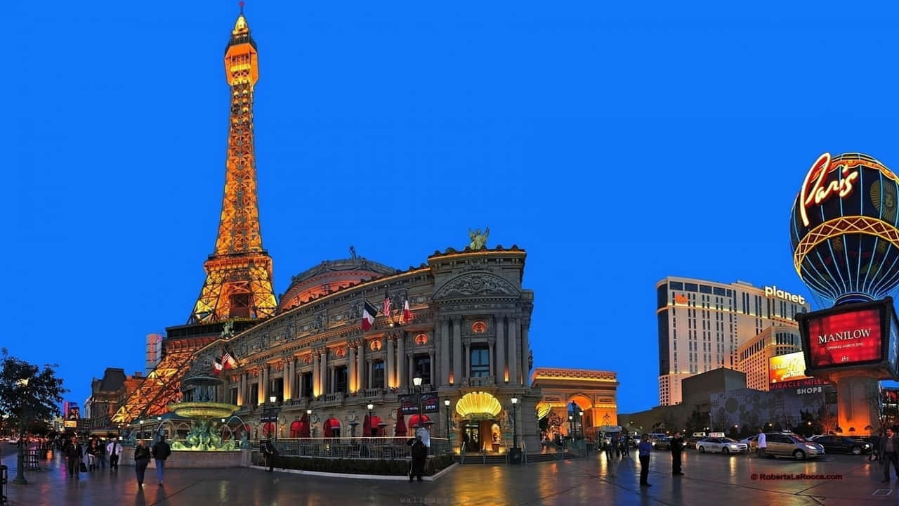 720p Las Vegas 桌布 壁紙 — 一座複製的艾菲爾鐵塔在深藍色的暮色天空中溫暖地發光，下方是拉斯維加斯繁忙的賭場廣場。